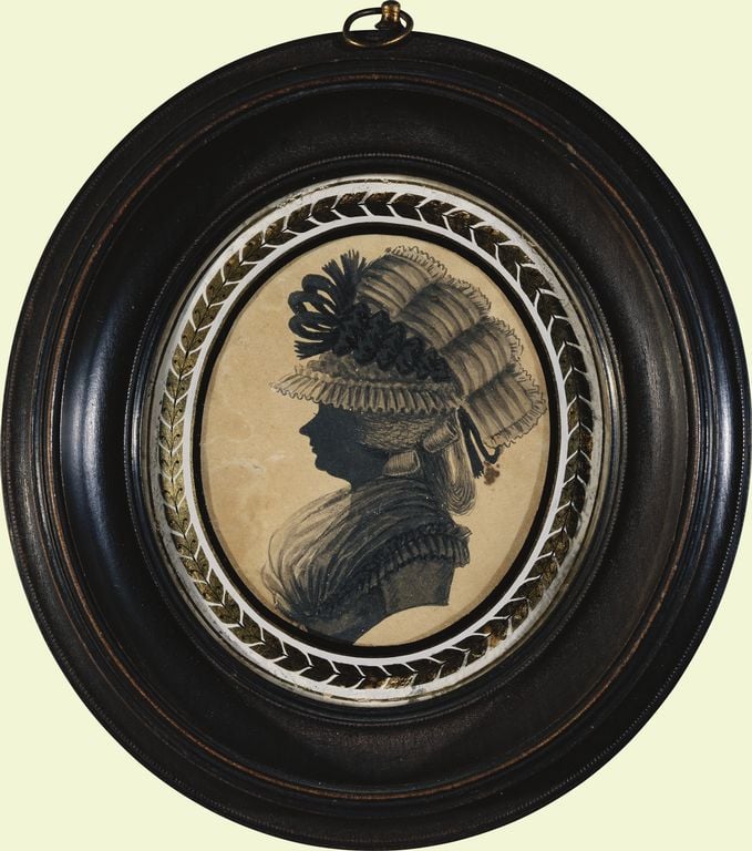Silhouette: female, bust length, profile left,wearing hat,  surrounded by decorative border