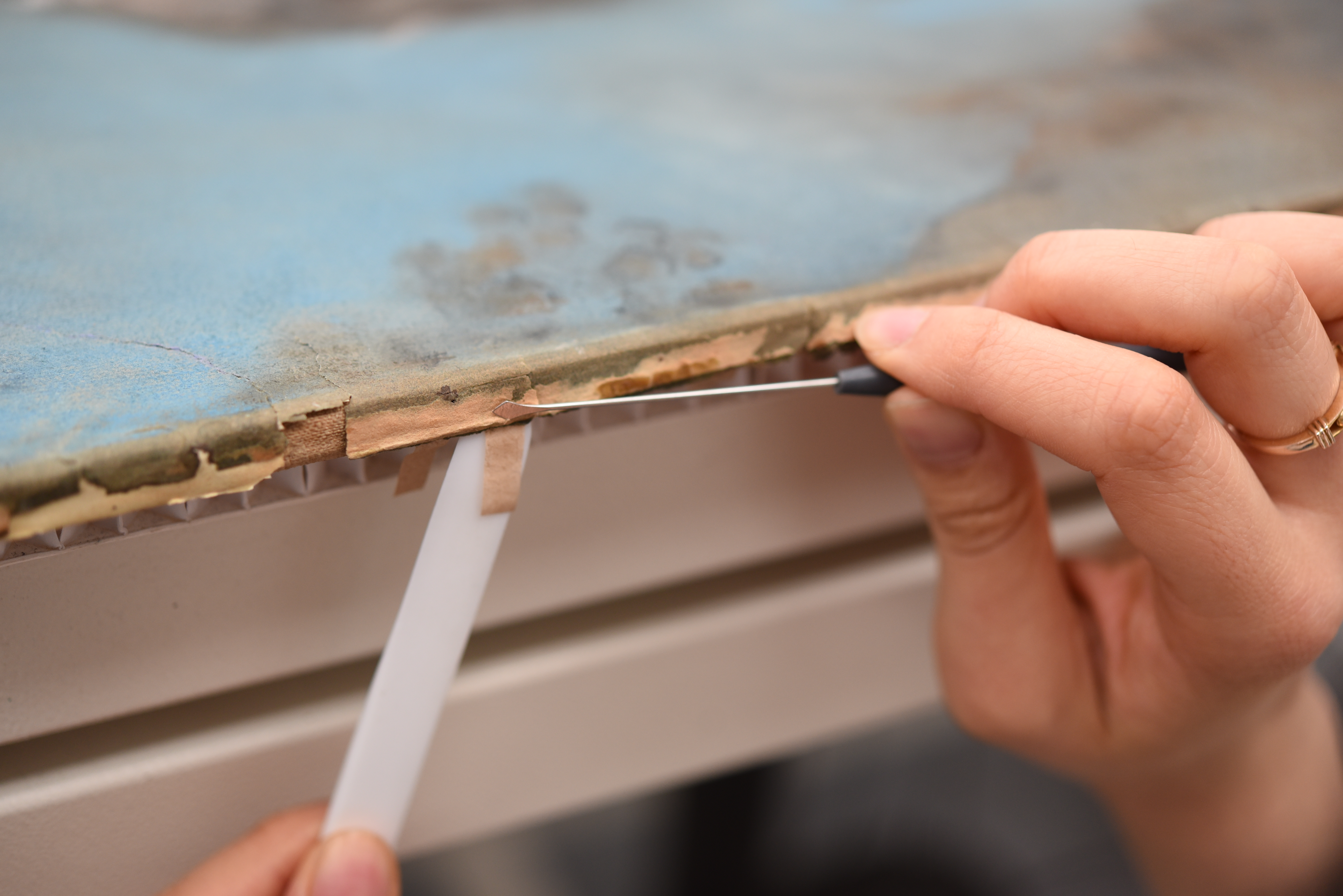 Conservators carefully reinforce the damaged edges of the paper support
