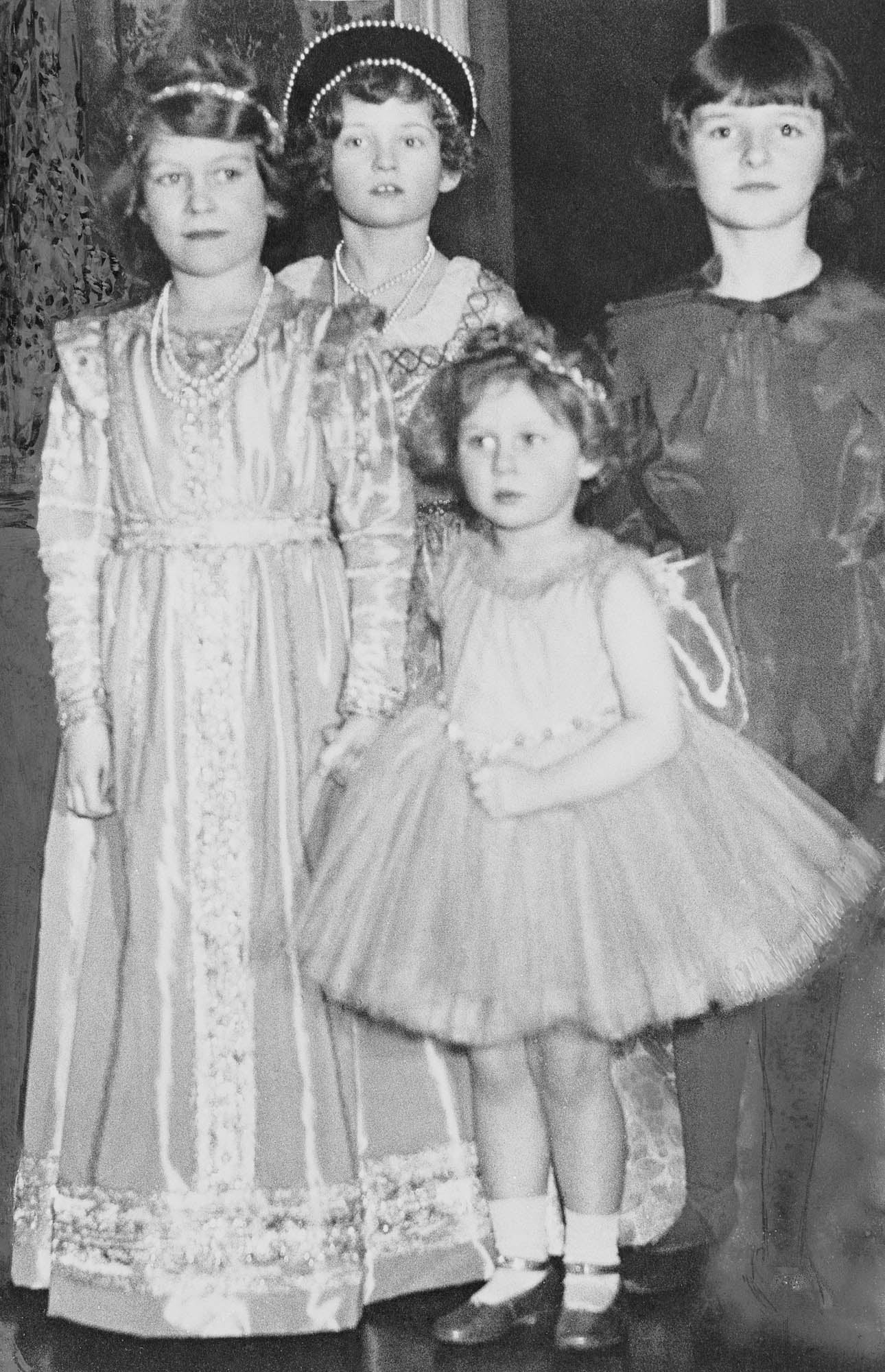 Photograph of Princess Elizabeth of York (1926- ) and Princess Margaret of York (1930-2002) attending a fancy dress party. The Princesses are photographed with two other unidentified girls. 