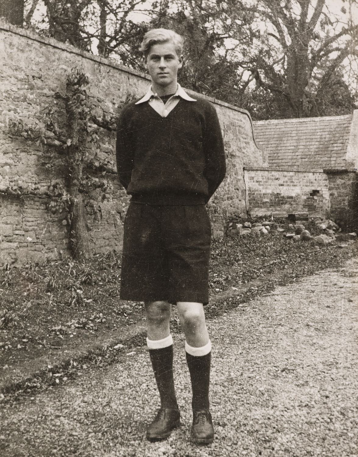 Photograph of Prince Philip, later HRH The Duke of Edinburgh, facing the viewer. He stands in a field and wears football kit. Photograph taken at Gordounstoun school.