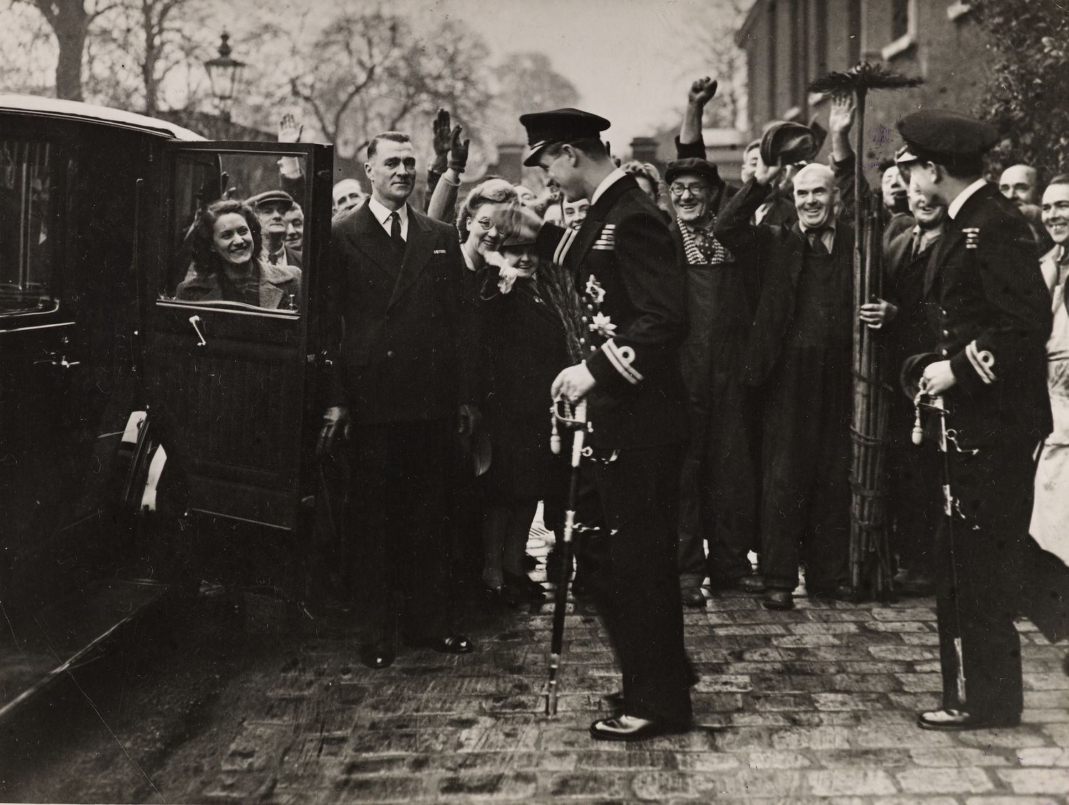 Photograph of Lieutenant Philip Mountbatten (b. 1921), later HRH The Duke of Edinburgh,&nbsp;leaving&nbsp;Kensington Palace on his wedding day.&nbsp;His groomsman David Mountbatten, Marquess of Milford Haven (1919-70) is standing behind him and a group of