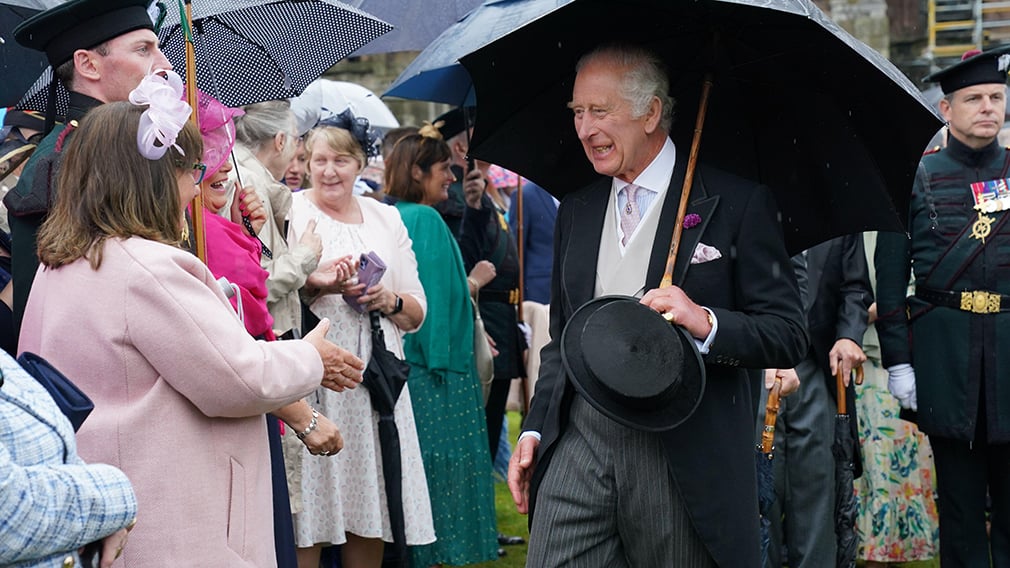 King Charles III host guests for a Garden Party at the Palace of Holyroodhouse. King Charles III holds an umbrella while greeting guests in the gardens of the Palace of Holyroodhouse.