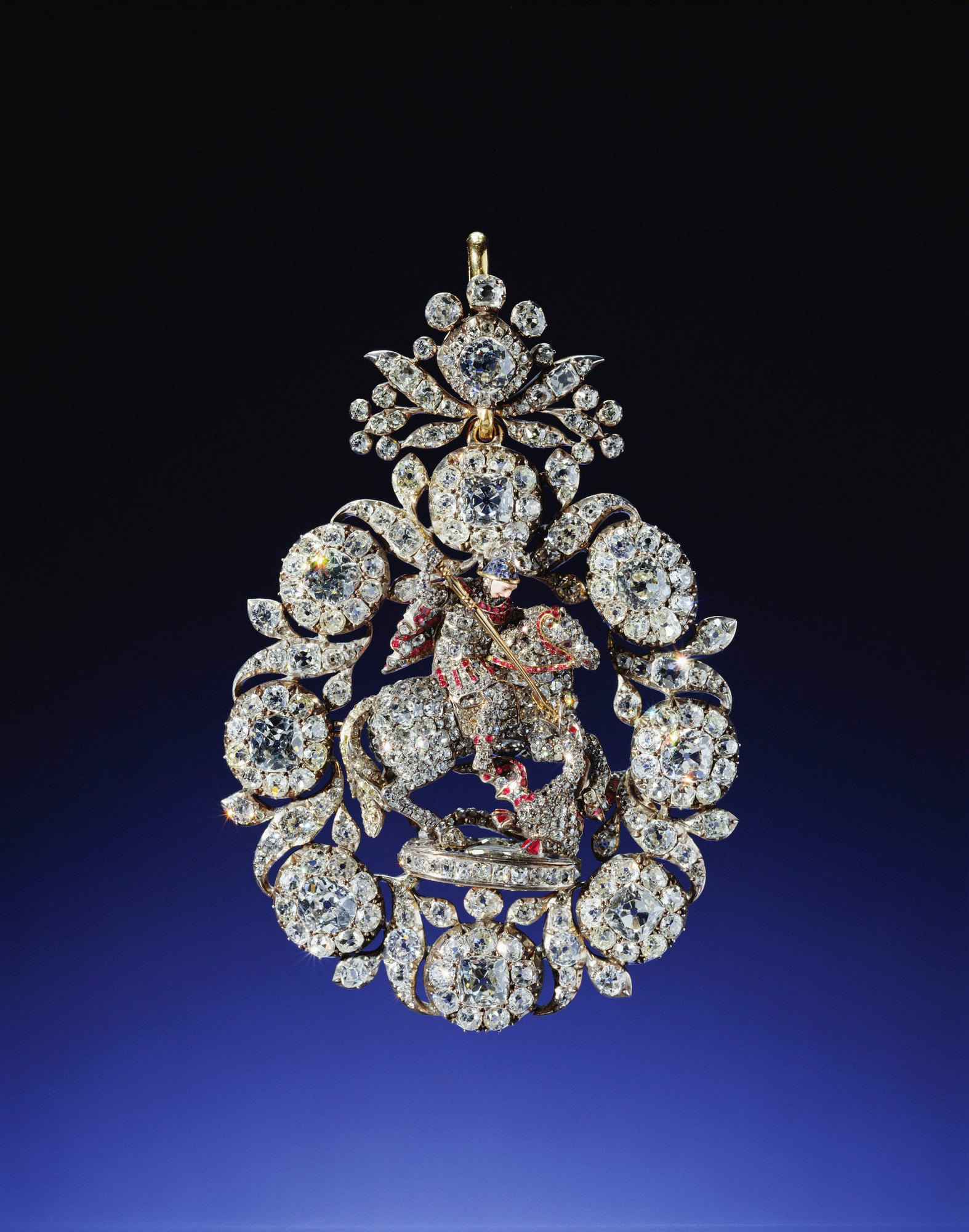Lesser George Lesser George of gold, jewelled all over, mainly with diamonds except St George's face which is enamelled and the sapphire helmet, and ruby harness and rubies on St George's cloak and on the dragon. In frame of diamond flowers, buds and leaves, surmounted