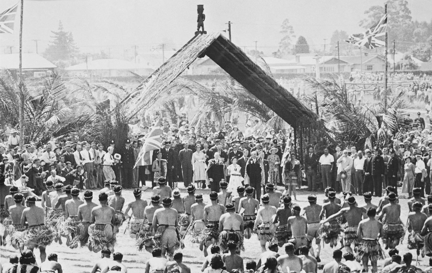 The Queen and The Duke of Edinburgh watch a demonstration of the 'haka' (a Maori war dance) at Arawa Park, Rotorua, in 1954 (RCIN 2707761)