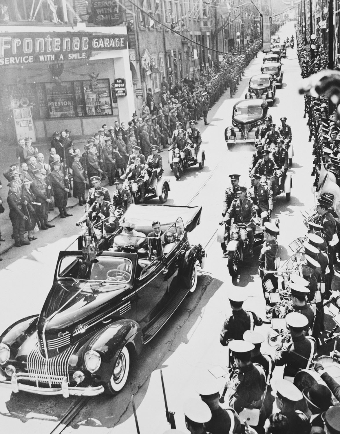 Photograph of King George VI and Queen Elizabeth being driven in an open topped limousine, past lines of crowds&nbsp;along Fabrique Street on their way to the Citadel, Quebec, Canada, during their visit to Canada in 1939.
King George VI (1895-1952) was th