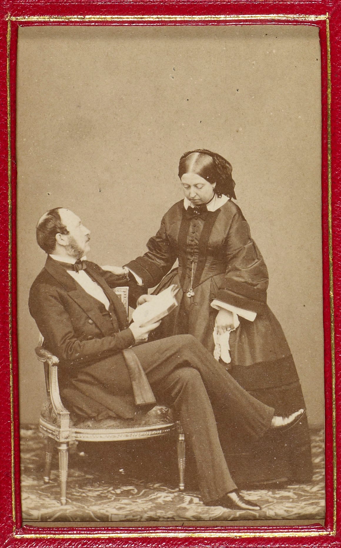 Carte-de-visite photograph of Queen Victoria (1819-1901) and Prince Albert, Prince Consort (1819-61). The Queen&nbsp;stands and looks&nbsp;down.&nbsp;Prince Albert is seated, facing right, and holds a book. He gazes up at Queen Victoria.