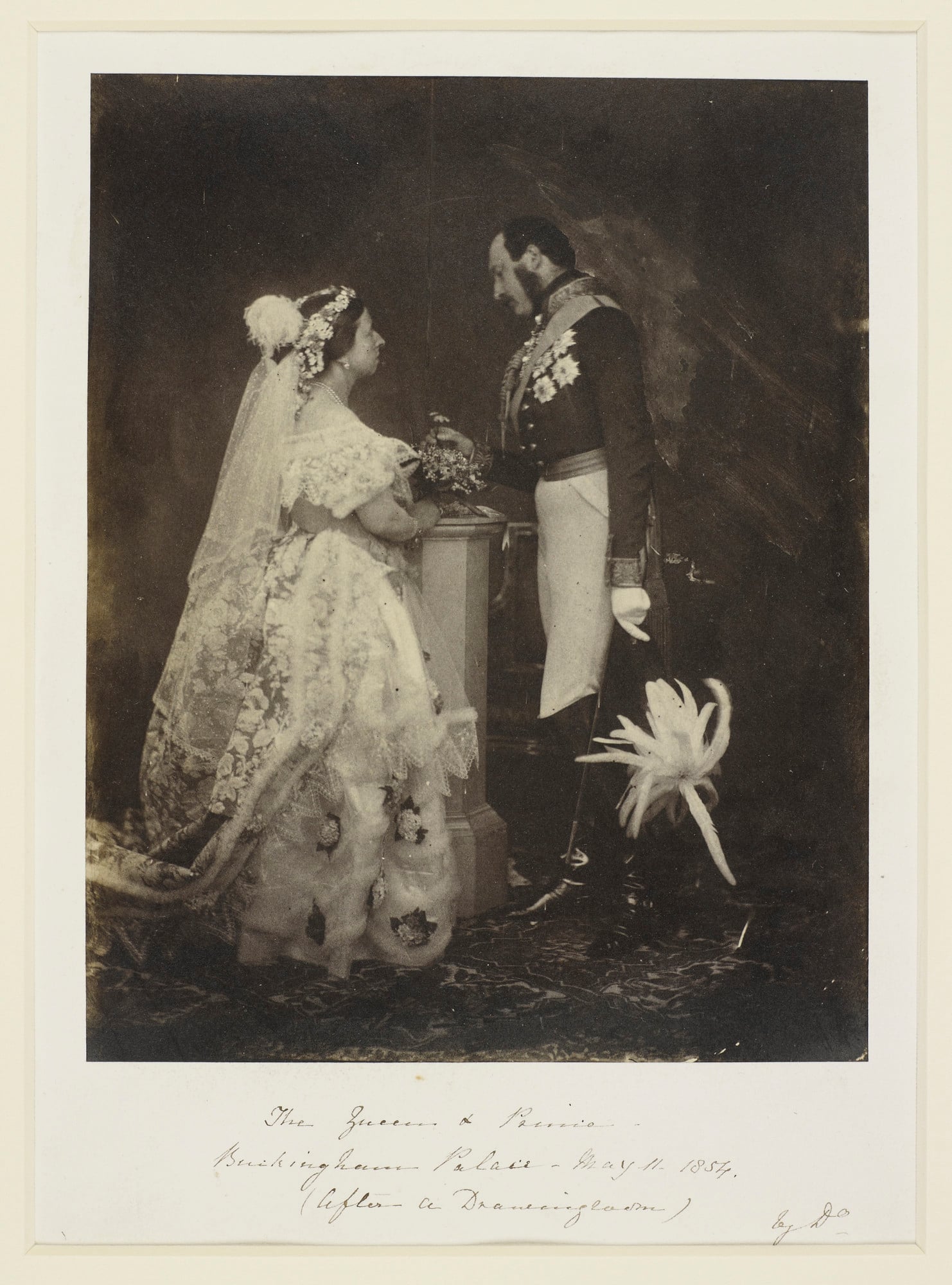 Photograph showing a full length portrait of Queen Victoria (1819-1901) and Prince Albert (1819-61). Queen Victoria stands in right side profile and wears formal court dress. Prince Albert stands in left side profile, holding a feathered hat in his left h