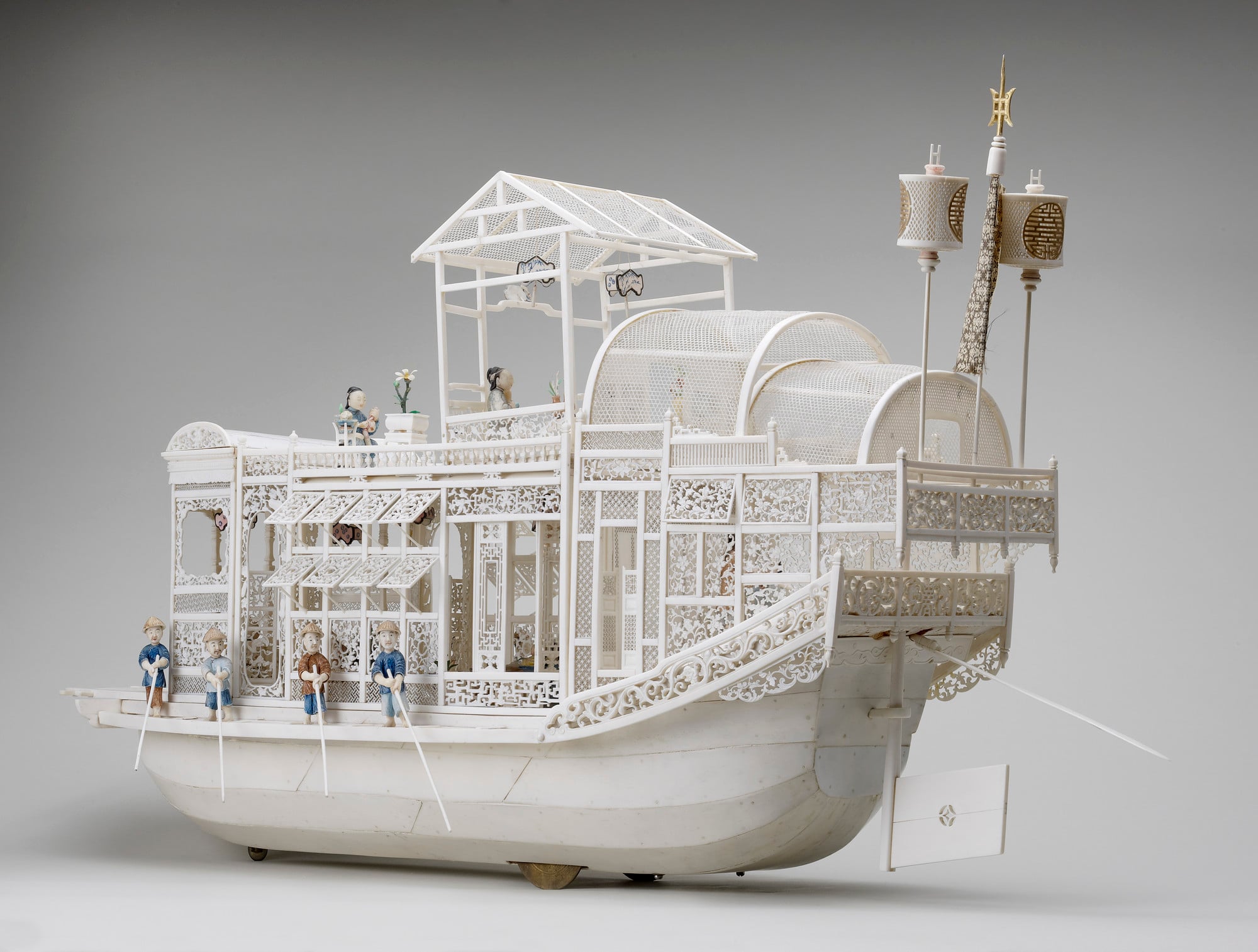 Chinese boat model A Chinese riverboat with an elaborate superstructure, the hull faced with long strips of ivory. Projecting underneath, a pair of black metal wheels near the stern, and a single wheel towards the prow. Within the high main chamber on deck, its walls, windo
