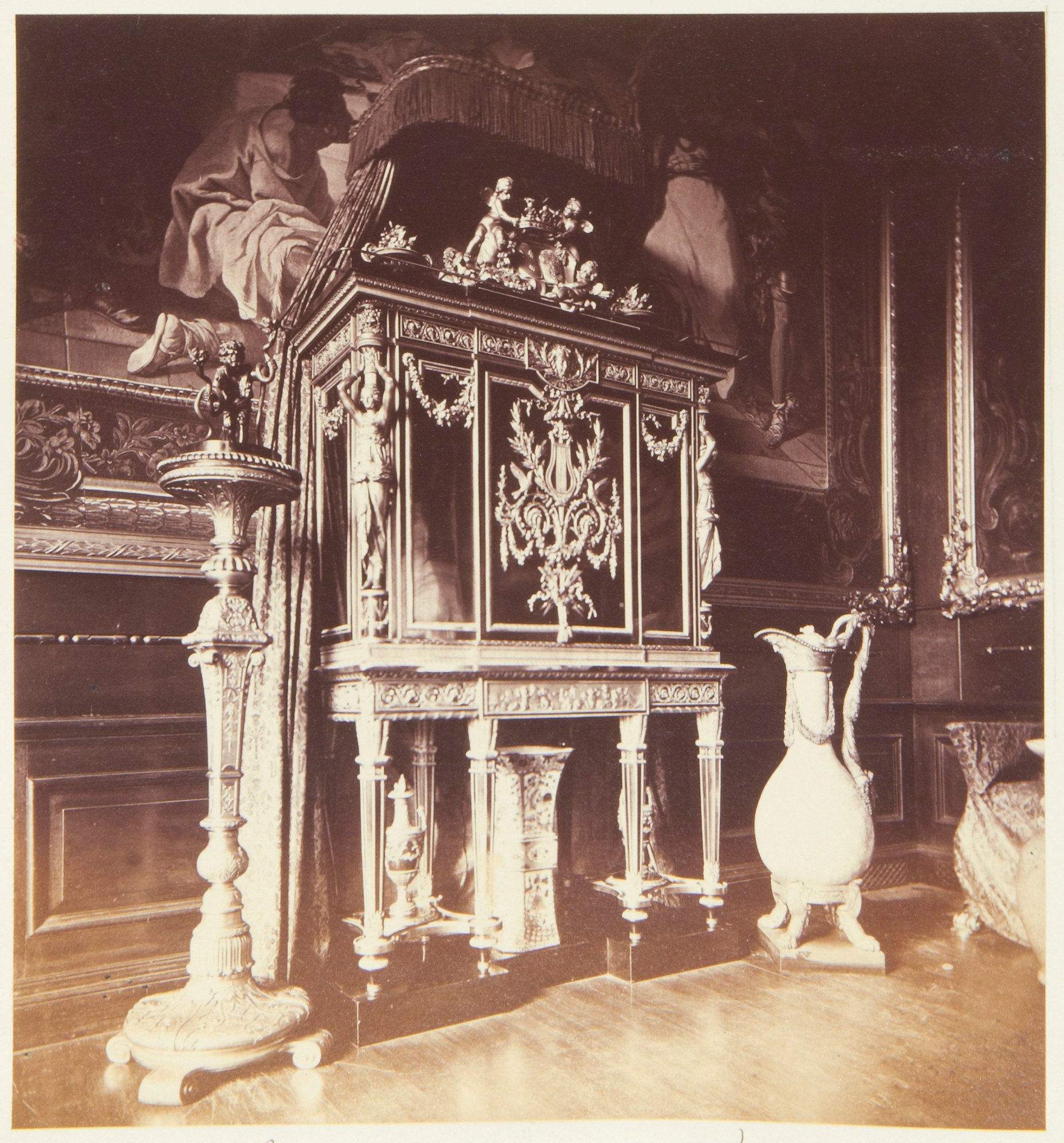 Photograph of some of the furniture in the Queen's Presence Chamber, Windsor Castle: large&nbsp;jewel cabinet by Riesener (RCIN 31207)&nbsp;with canopy above, a large chinese porcelain jar on floor and candle stand&nbsp;(RCIN 33389)&nbsp;with figurative c