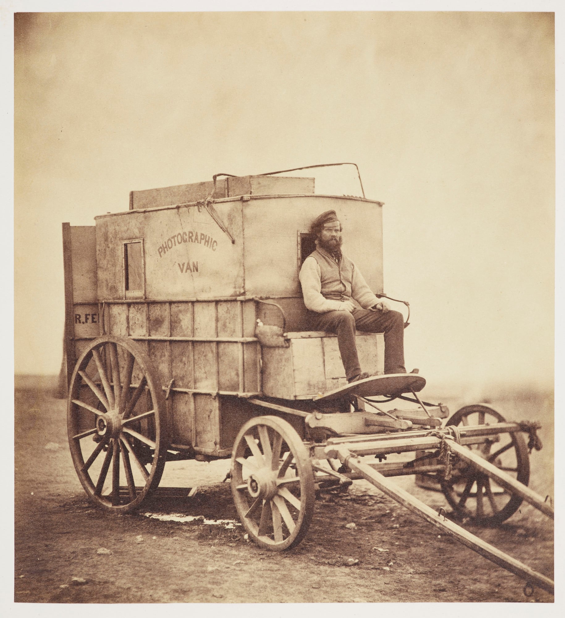 Photograph of Roger Fenton's horse-drawn photographic van, with his assistant Marcus Sparling seated at the front. The van is facing partly right and has 'PHOTOGRAPHIC VAN' printed on the side. 

Roger Fenton used the wet collodion photographic process 