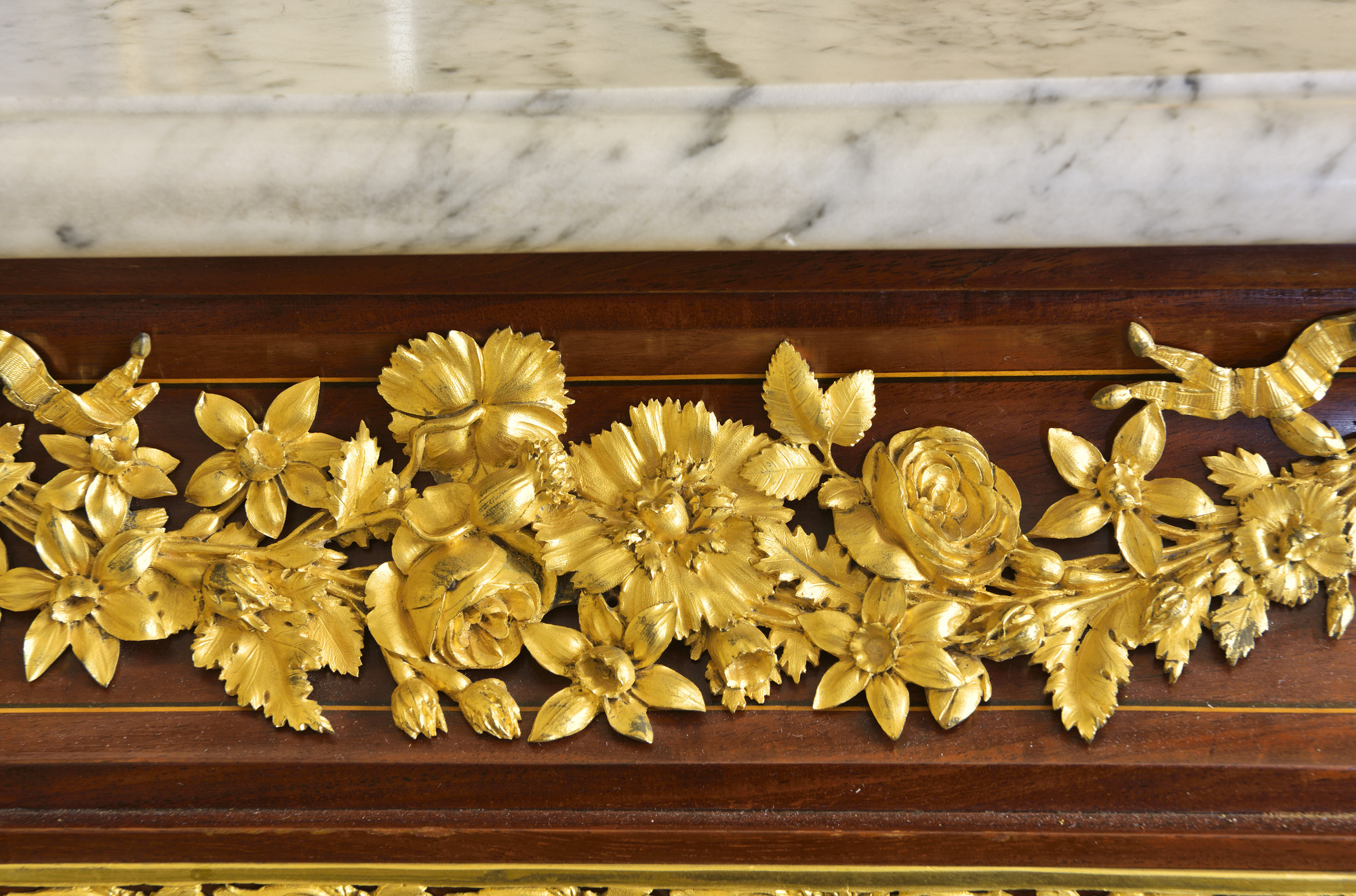Rectangular cabinet veneered in mahogany with white marble top and gilt bronze mounts. The concave frieze above two doors with gilt bronze mounts of garlands of flowers, the door&nbsp;panels edged with gilt&nbsp;bronze foliage mounts. The angles with cant