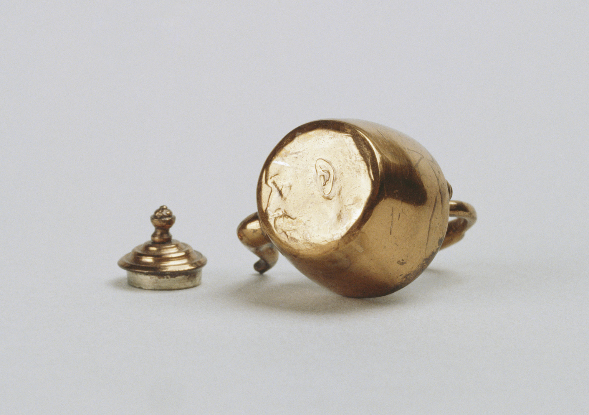 Miniature copper kettle, fixed balil handle and swan-neck spout. Formed from a coin, the King's head still visible on the base