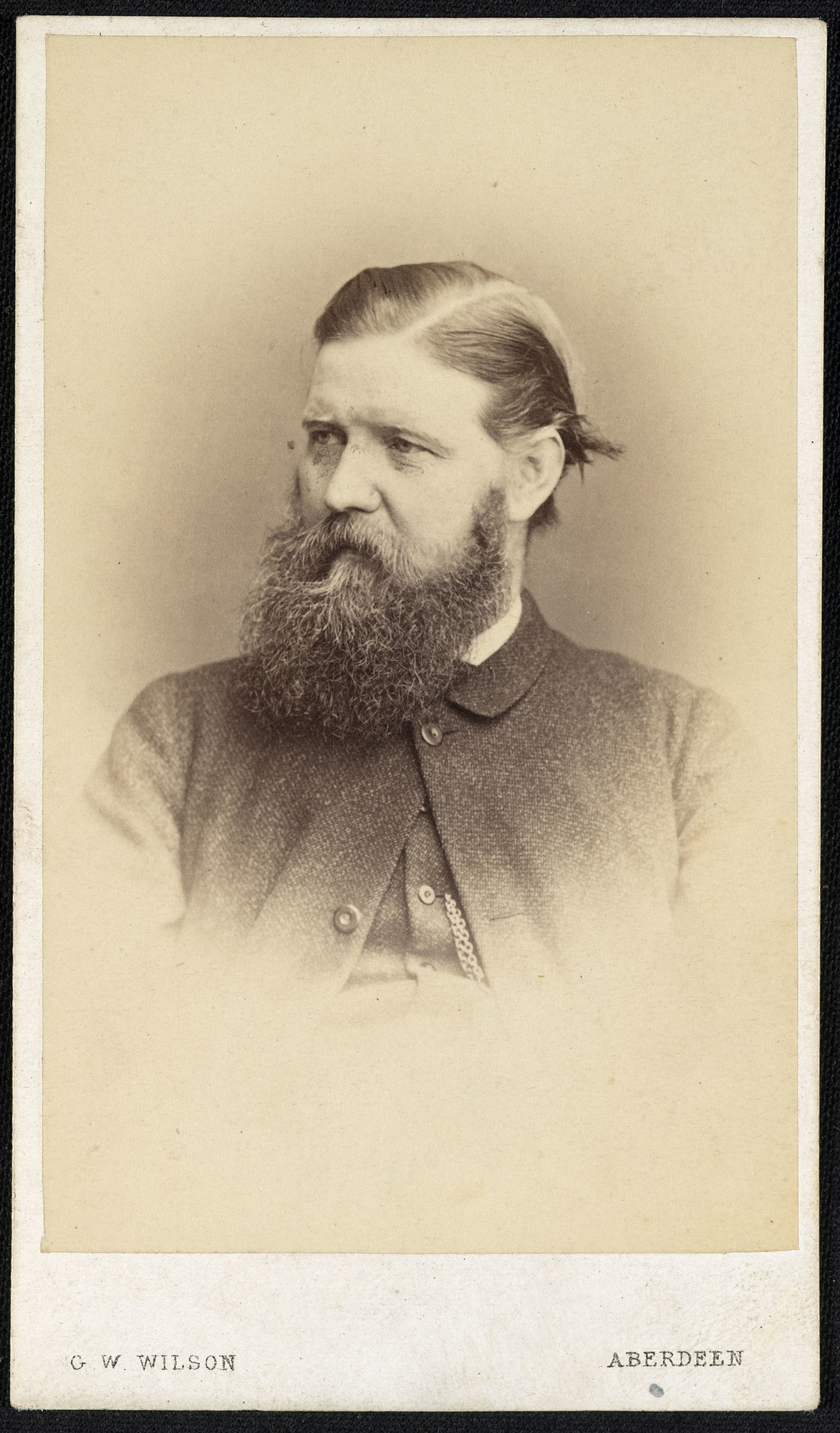 Photograph of the photographer George Washington&nbsp;Wilson (1823-93)&nbsp;in head and shoulders length portrait, facing three-quarters to the left. He wears a jacket buttoned at the top with a watch chain visible hanging from his waistcoat.