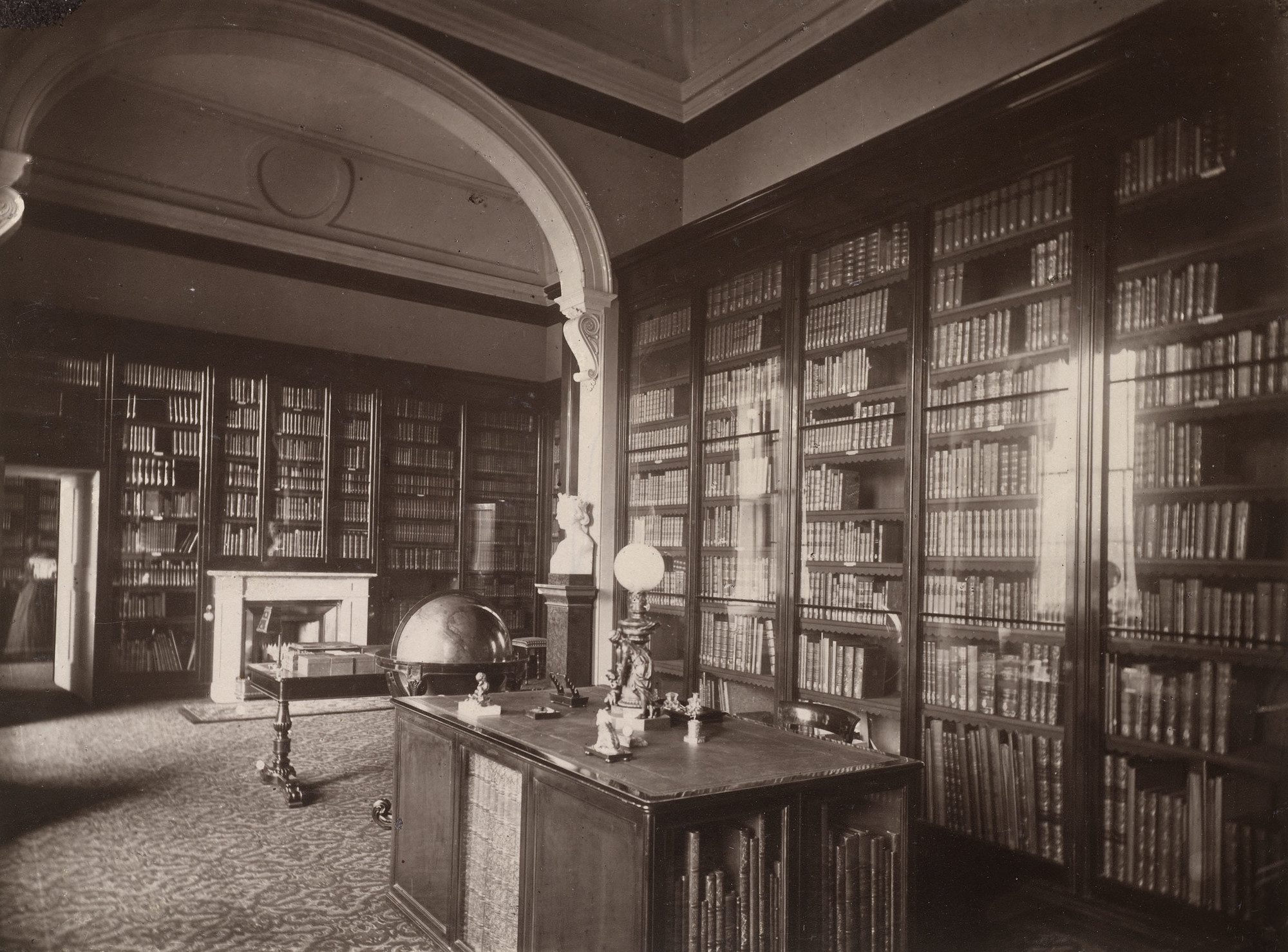 The Prince Consort's Library, Buckingham Palace Photograph of the Prince Consort's Library, a room divided into two by an arch. The walls are lined with glazed bookcases, and there is a bookcase-library table in the centre. Beyond this is a globe and another table.