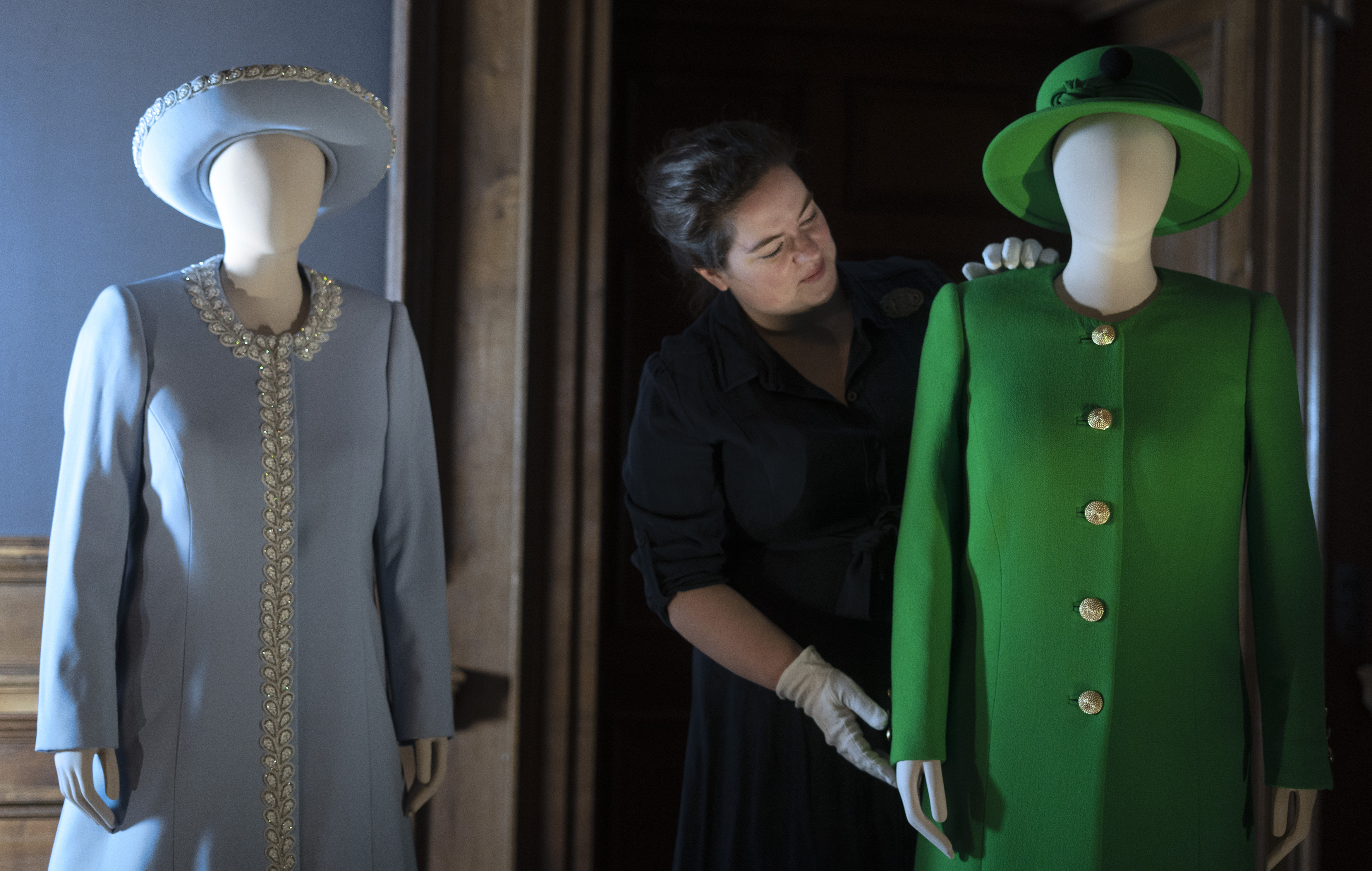 A curator puts finishing touches to Her Majesty The Queen's Platinum Jubilee outfits, which are on display at the Palace of Holyroodhouse