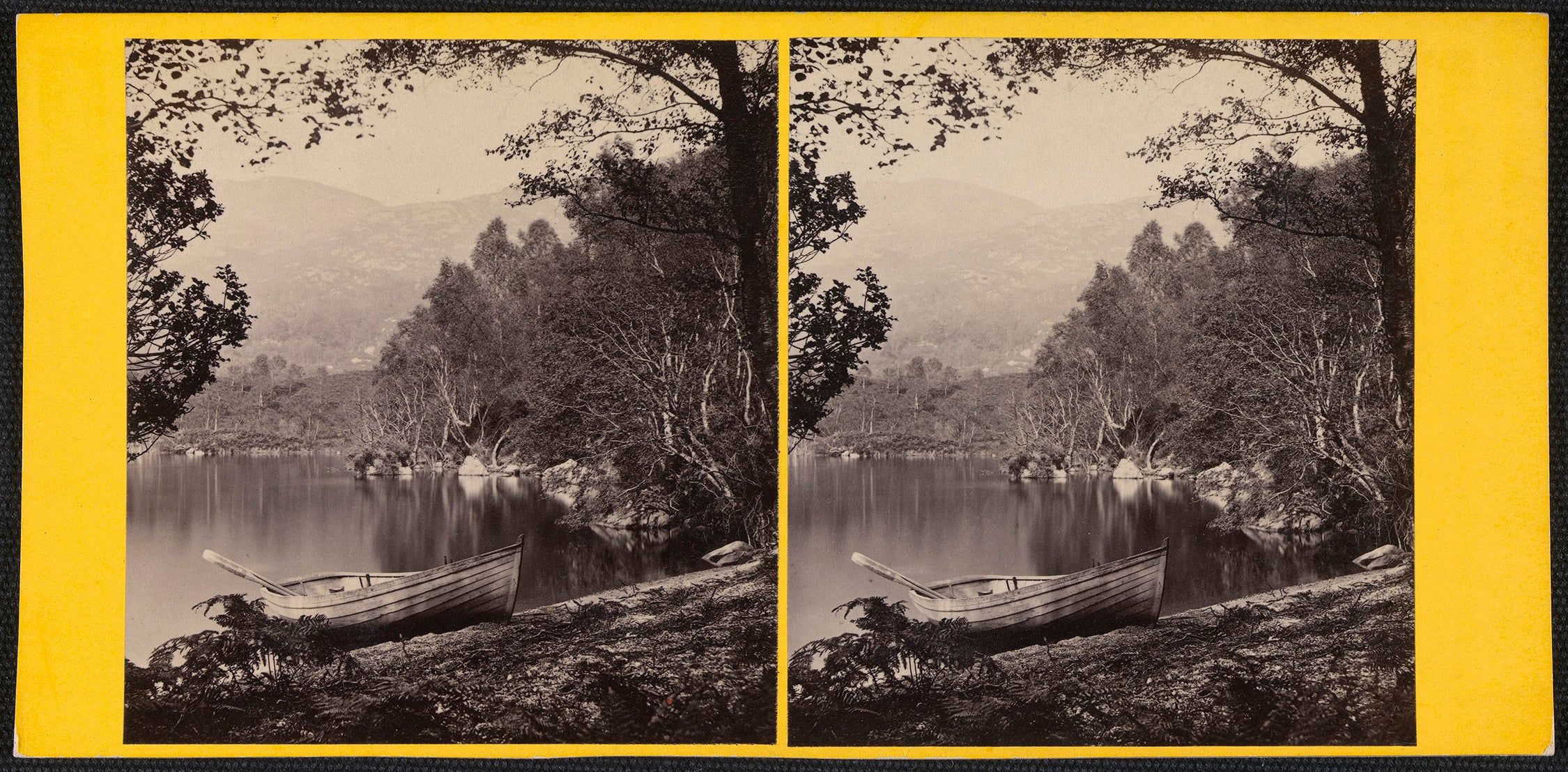 Stereoscopic photograph&nbsp;of a rowing boat moored at the side of Loch Katrine with trees in the foreground framing a view towards hills in the distance. 
Sir Walter Scott immortalised&nbsp;Loch Katrine and the Trossachs&nbsp;in the Scottish Highlands b