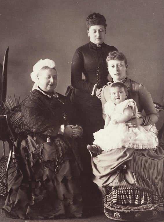 Photograph showing, from left to right: Queen Victoria, seated, smiling; Beatrice, Princess Henry of Battenberg, standing; Victoria, Princess Louis of Battenberg, seated, with Princess Alice of Battenberg on her lap.
Despite her great sorrow at the death 