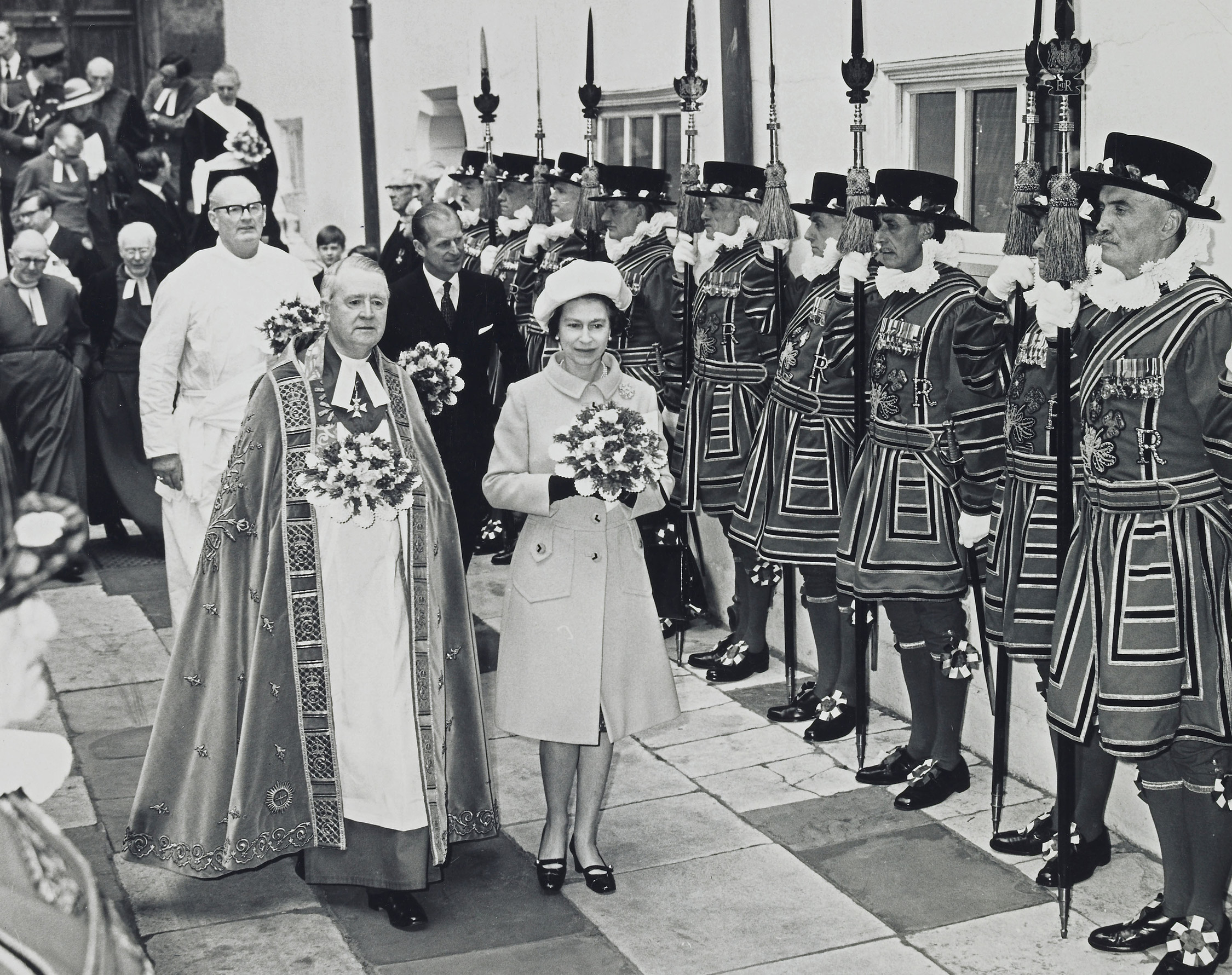 b/w. Queen and Dean of Westminster ; followed by Philip and other clergymen ; leaving Westminster Abbey after Maundy service, passing Guard of Honour of the Yeomen of the Guard.