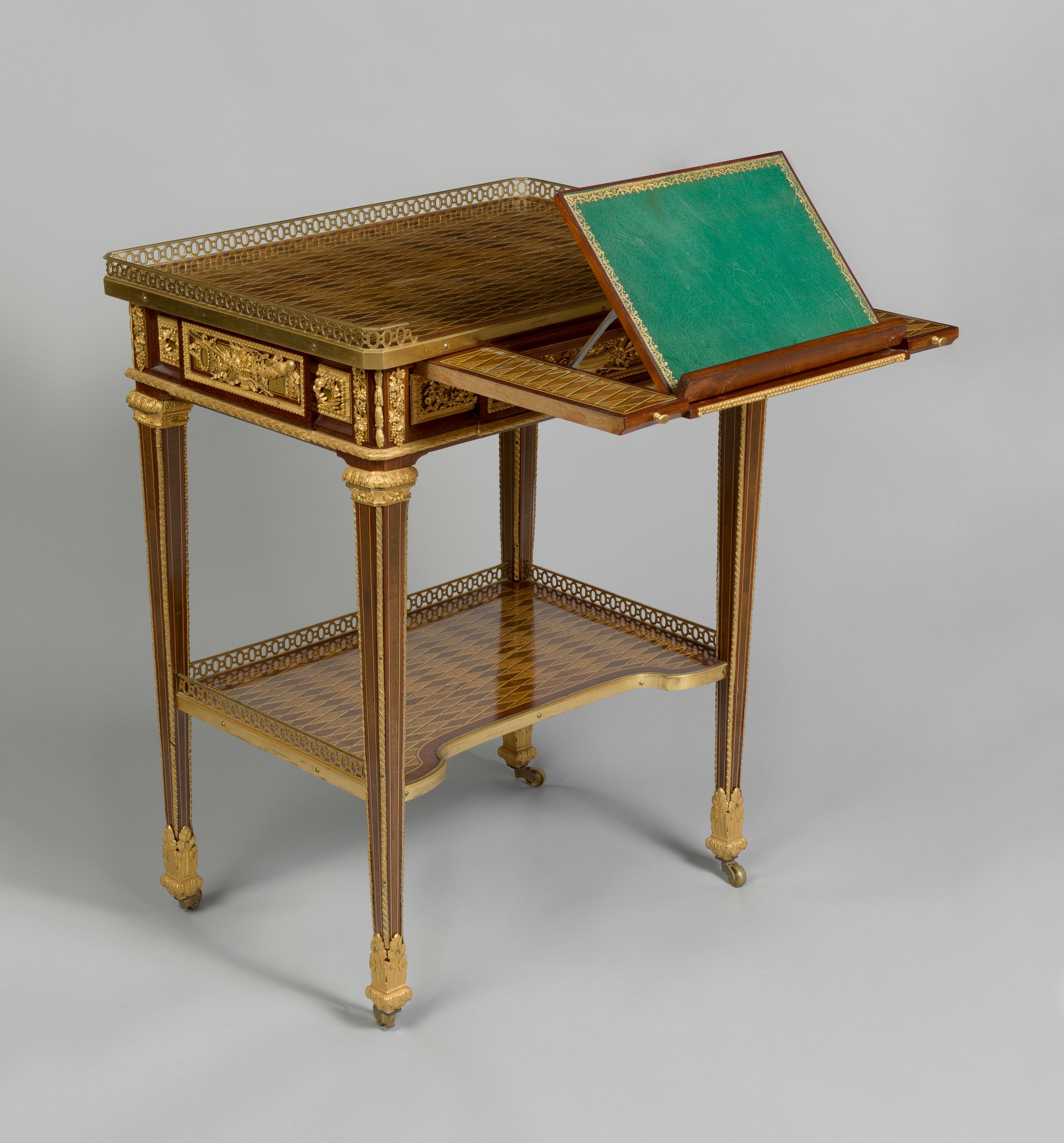 The rectangular trellis parquetry top with pierced three-quarter gilt bronze gallery above a&nbsp;panelled frieze with&nbsp;a drawer&nbsp;on one long side incorporating a&nbsp;ratcheted&nbsp;leather-lined writing-slide, and a small pen drawer on the right