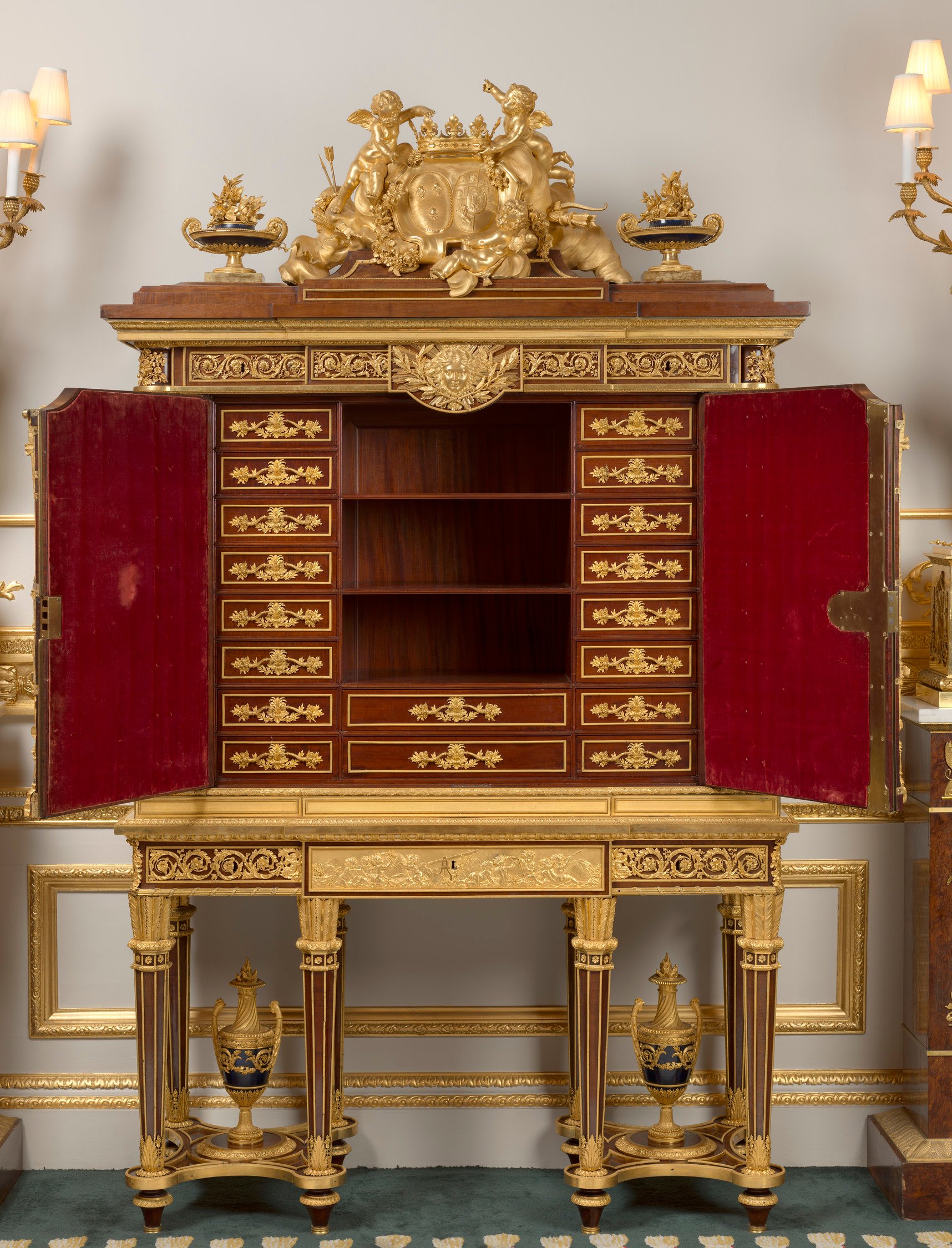 Mahogany and gilt bronze cabinet; superstructure with a group of putti holding a crown above conjoined coats-of-arms of the Bourbon and Savoy families flanked by vases. The frieze with three drawers; above two cabinet doors with scrolling foliage enclosin