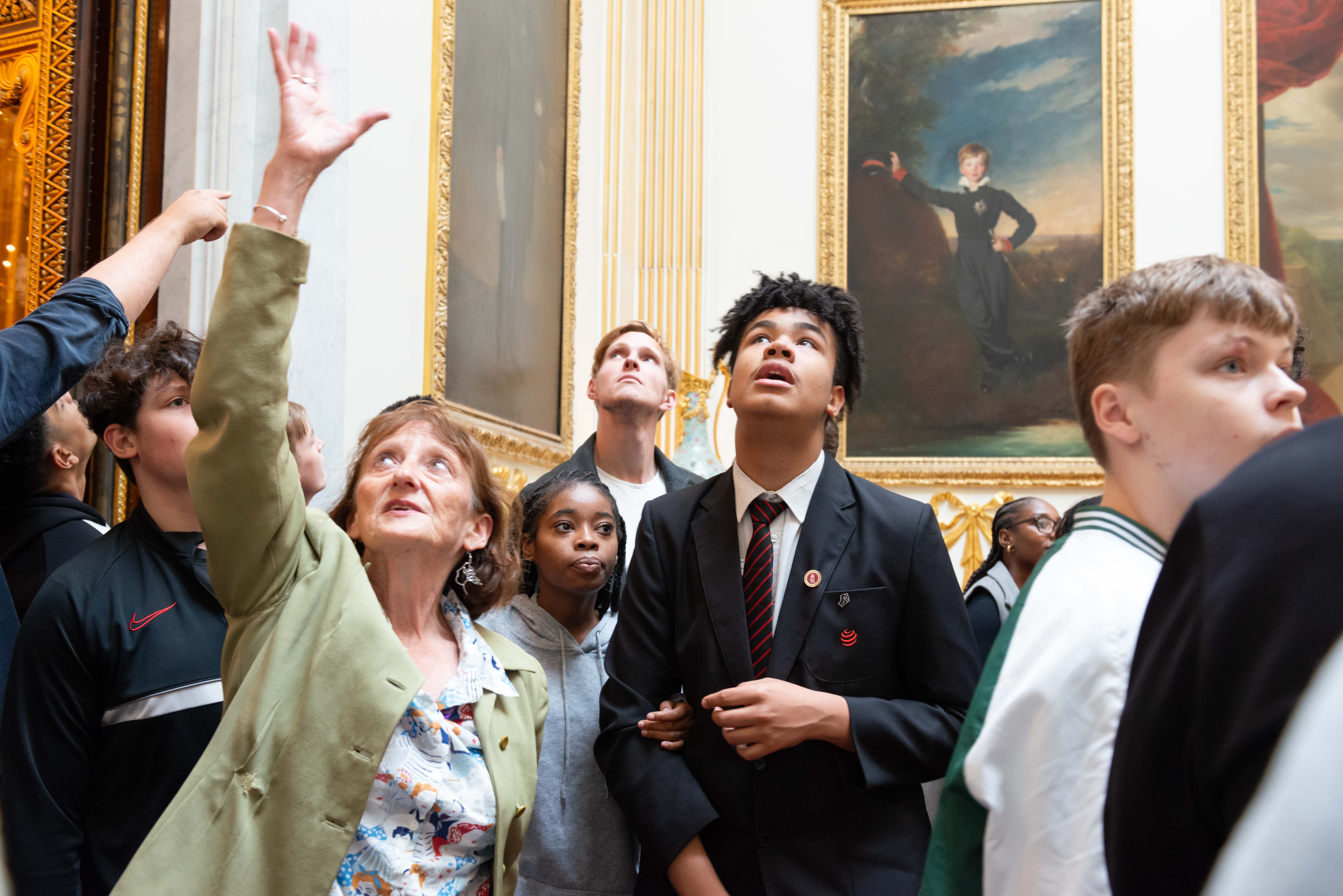 Teenage students look upwards towards the ceiling of the Grand Staircase
