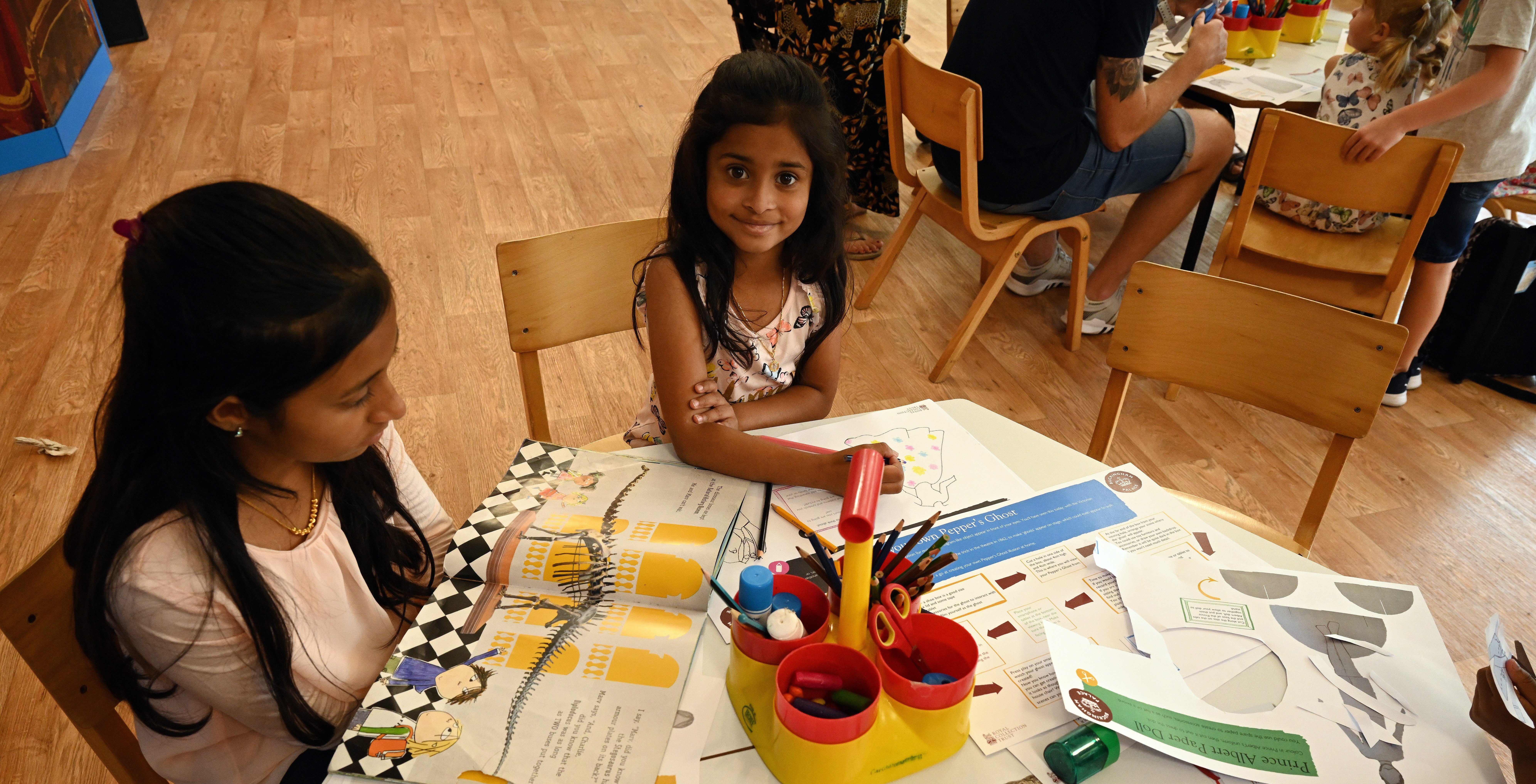 The Family Pavilion at Buckingham Palace. Two children sitting at a table with craft and drawing activities on it.