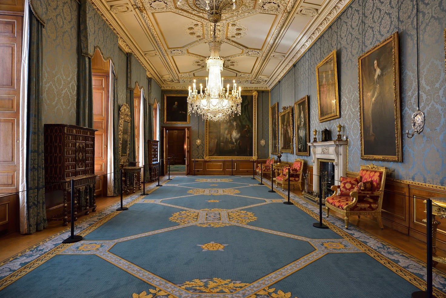 View of the Queen's Gallery with blue carpets, blue walls and grand paintings