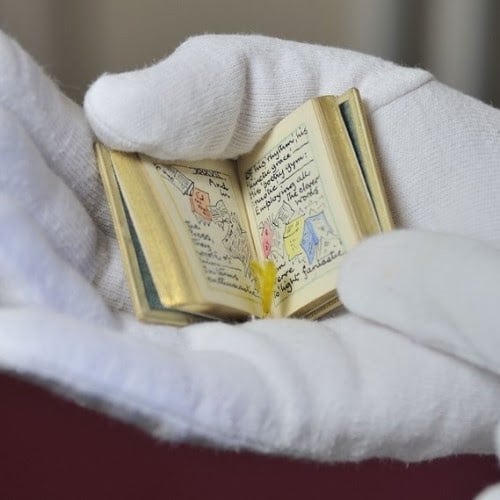 miniature book open in palm of a hand