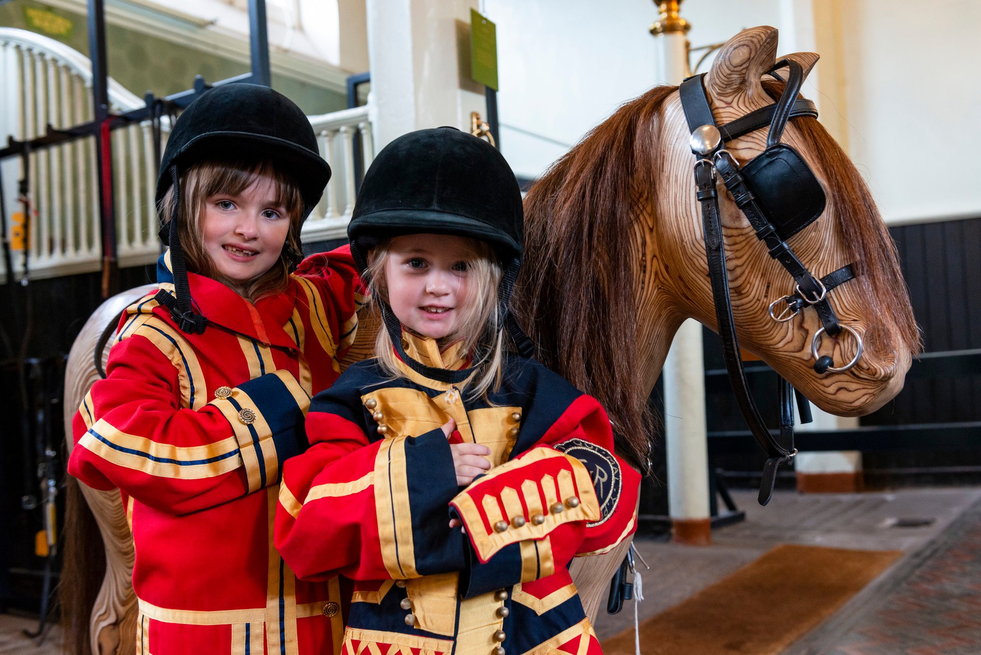 Children dressing up next to a wooden horse