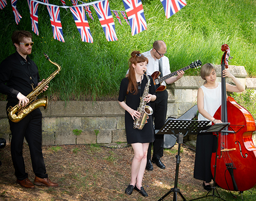 A jazz band play outside with union jack bunting in background