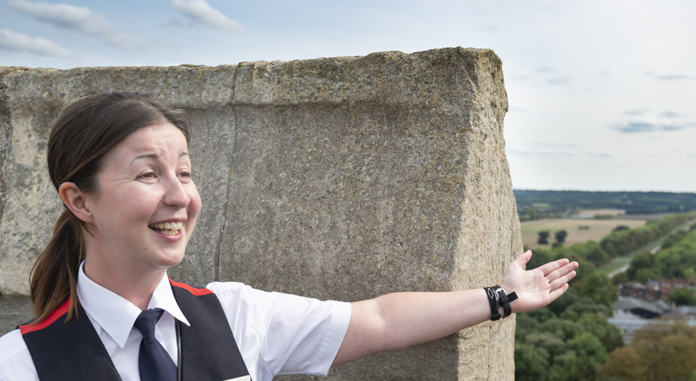 Our expert guide will point out highlights in the view from the top of Windsor Castle's Round Tower. A Warden pointing outwards towards the view from the Castle.