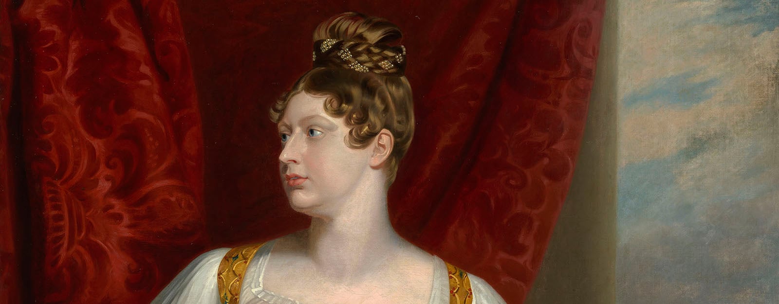 A woman seated looking left. Her hair in a plaited bun.