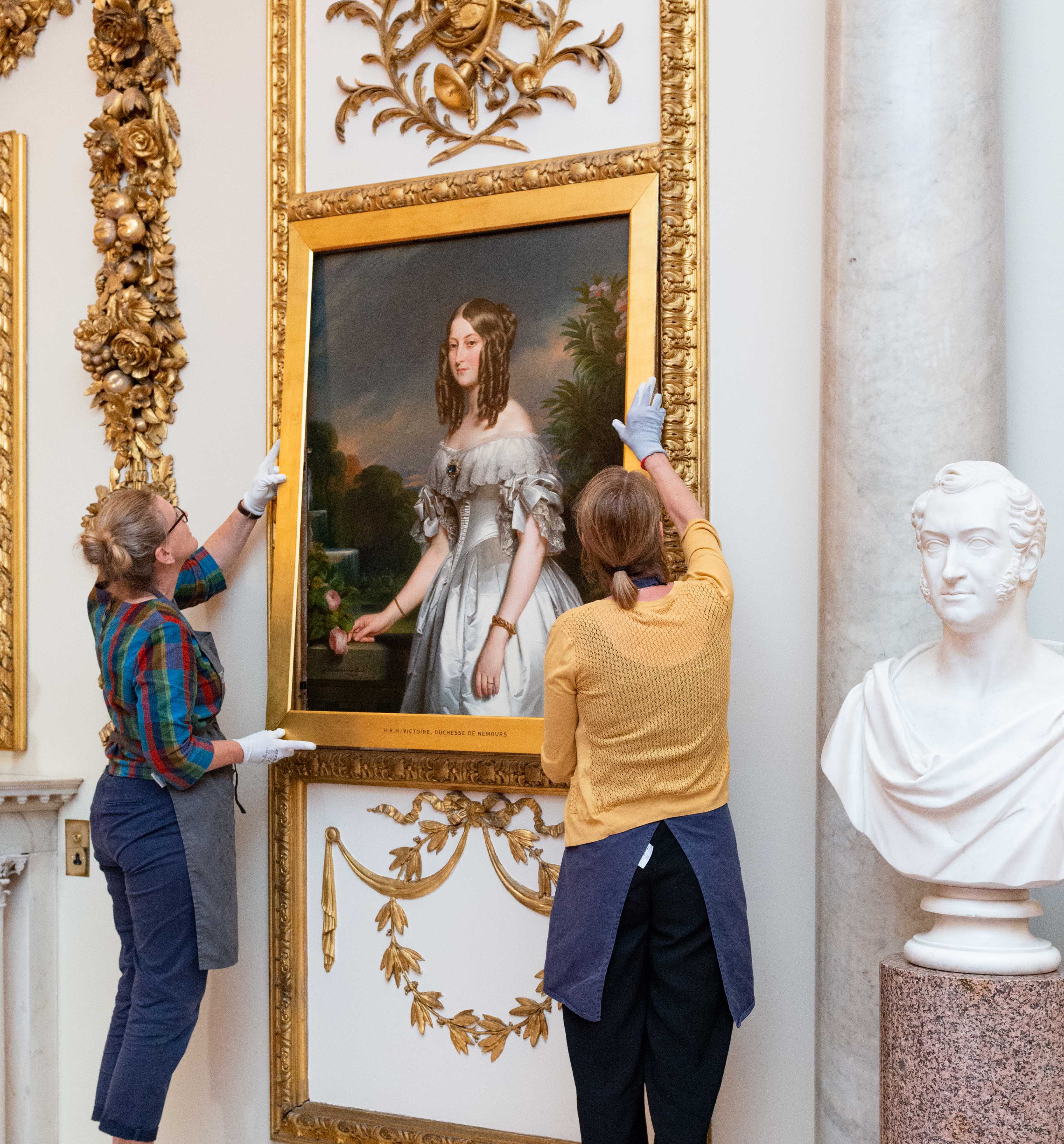 Rehanging of the conserved paintings in the Marble Hall, Buckingham Palace Two technicians hang one of the cleaned and conserved paintings in the Marble Hall, Buckingham Palace