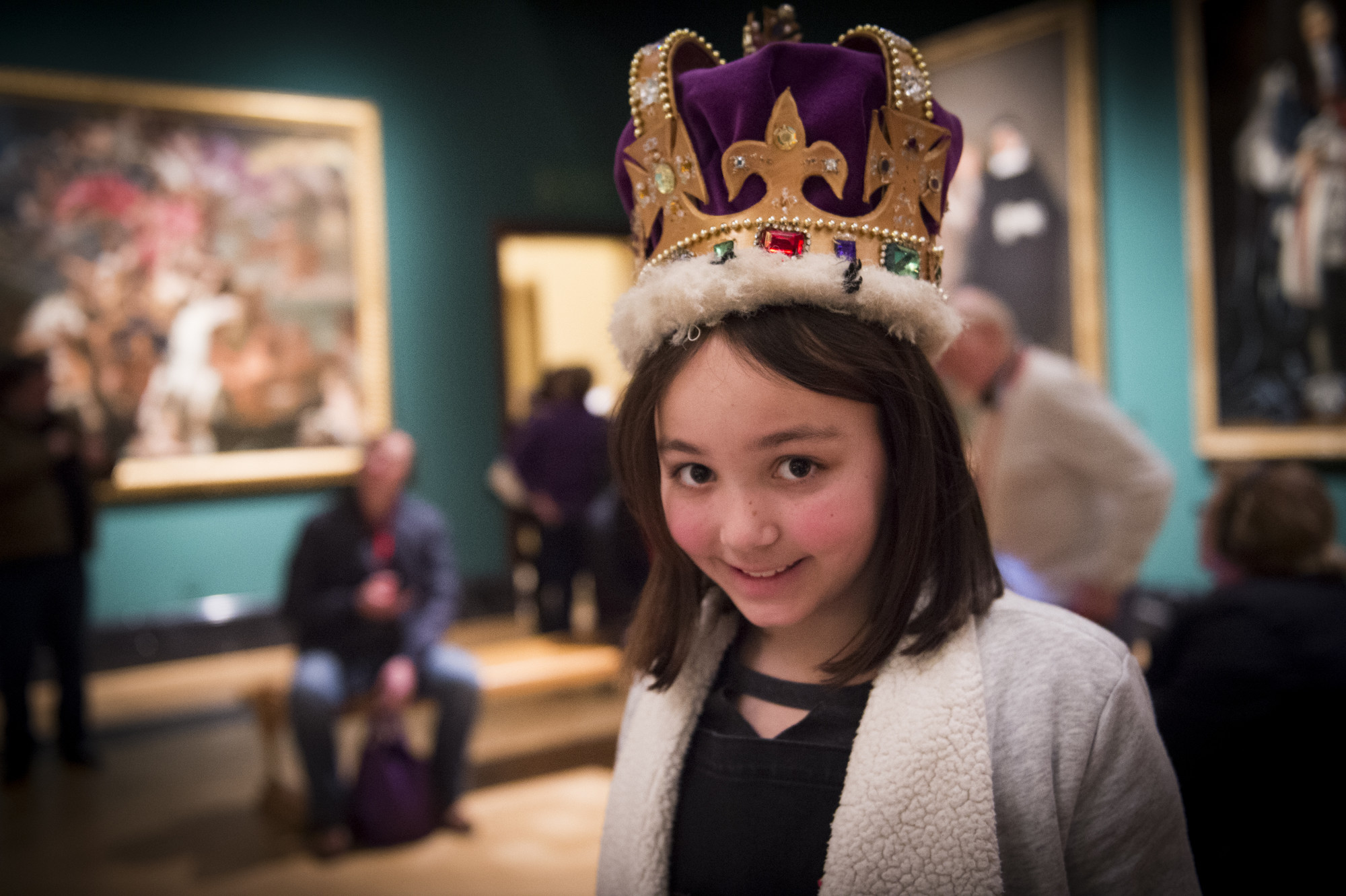 A girl is wearing a crown in an art gallery