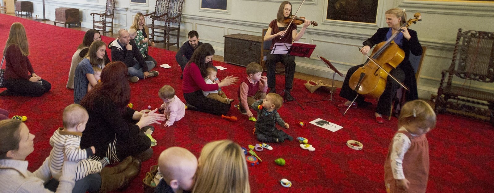 Adults and toddlers listen to a cellist and violinist 