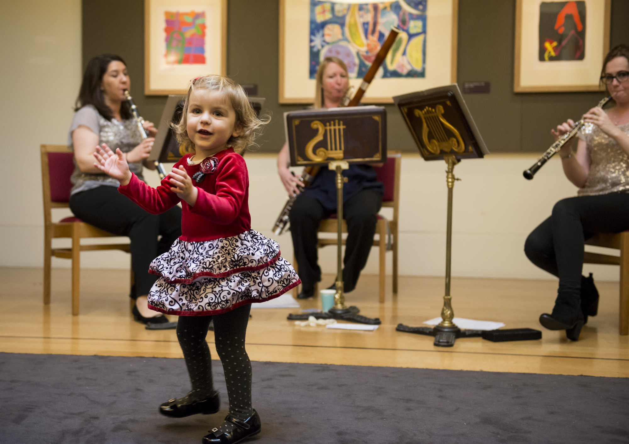 A little girl is dancing in front of classical musicians