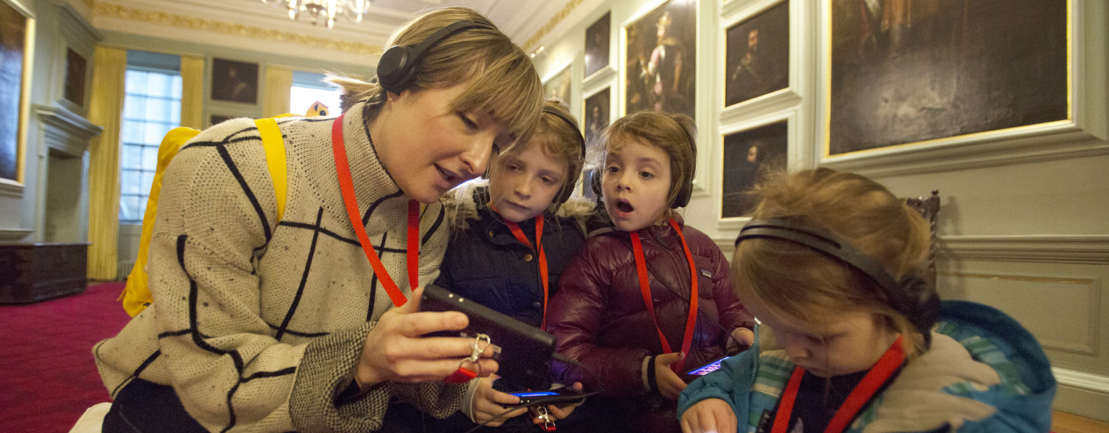 Woman and 3 children looking at multimedia guides in the Great Gallery, Palace of Holyroodhouse