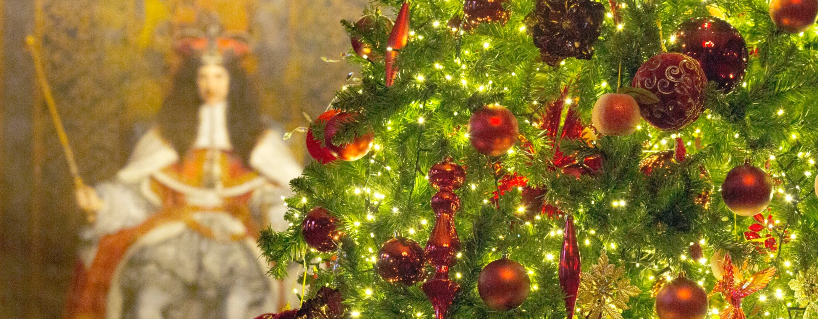 Close up photograph of a Christmas tree in front of a painting of Charles II in the Throne Room, Palace of Holyroodhouse