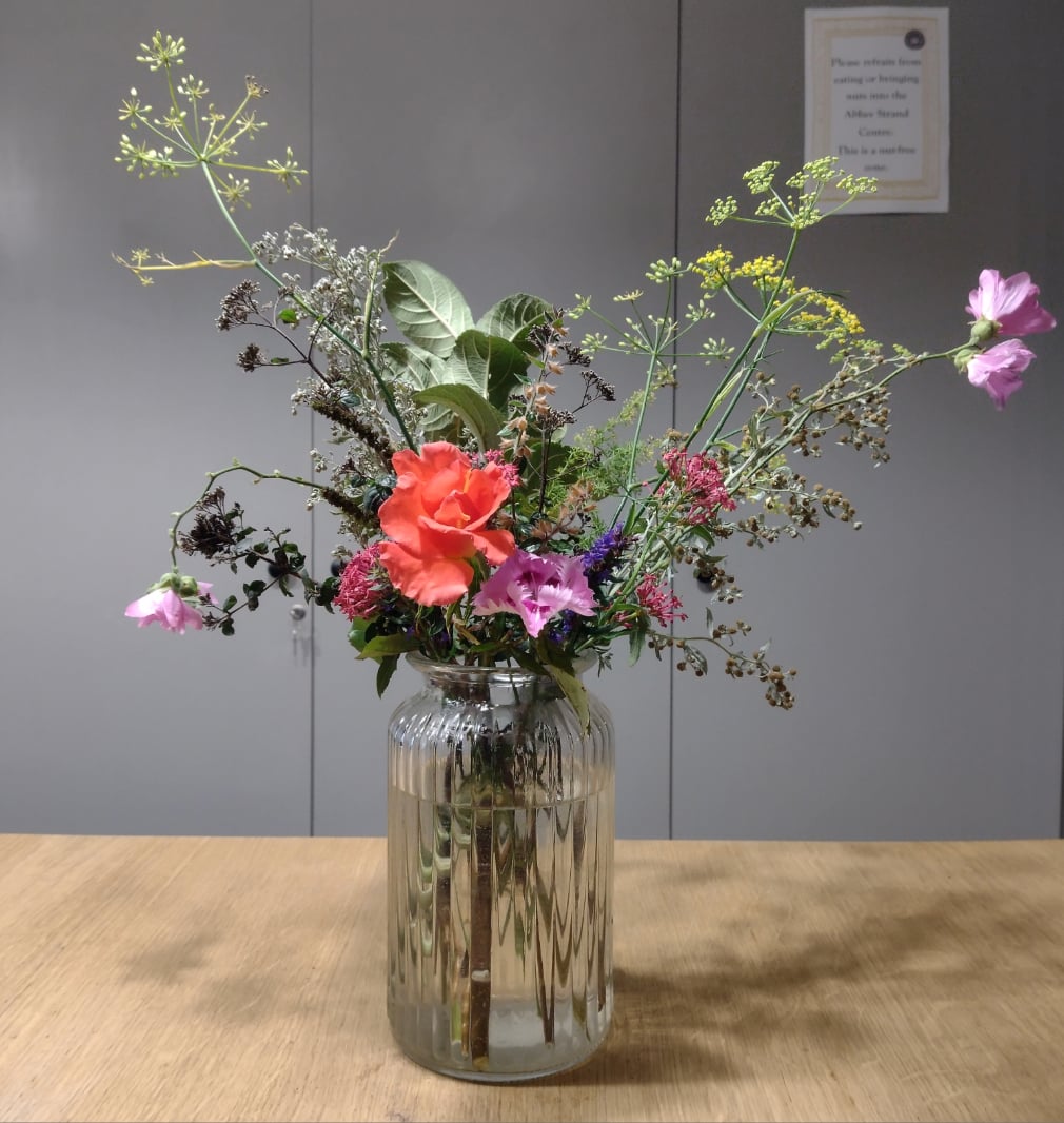 A vase of flowers sitting on a wooden desk