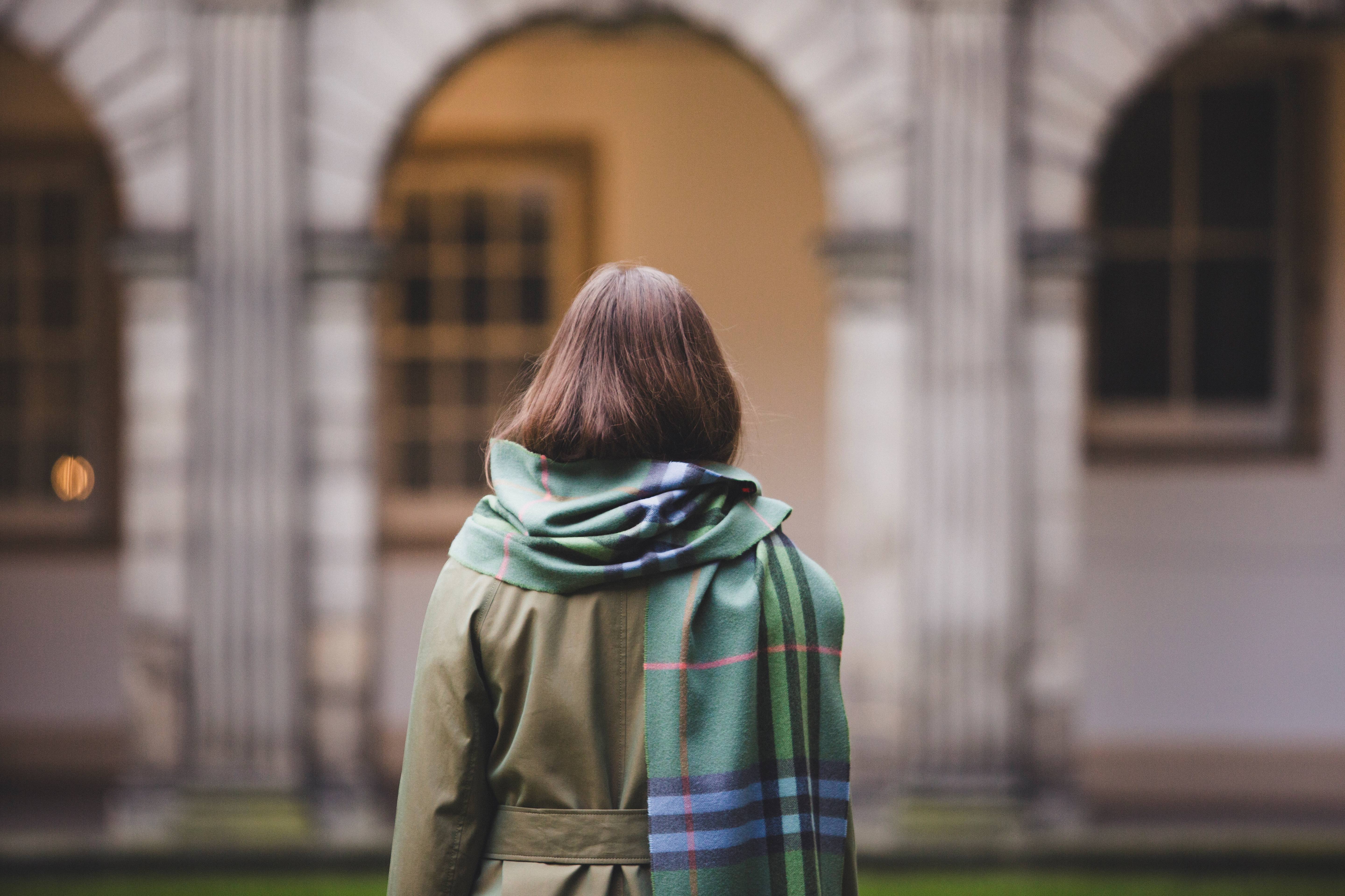 Women stands in a quadrangle wearing a trench coat and cashmere scarf