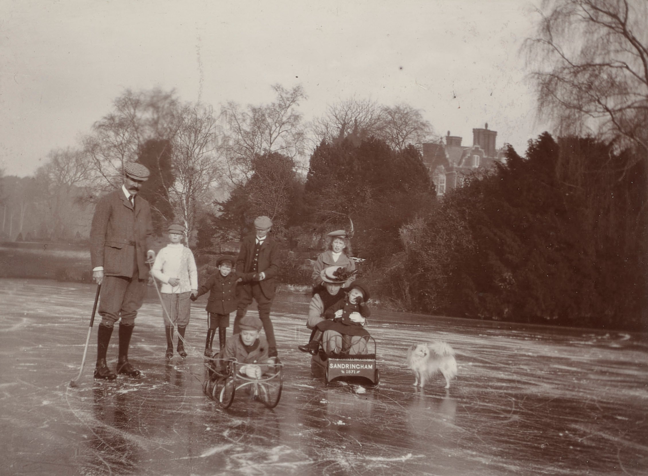 George V and Queen Mary enjoying the wintery surroundings and sledging on the frozen lake at Sandringham (RCIN 2303331) A black and white photograph of people ice skating on a frozen lake