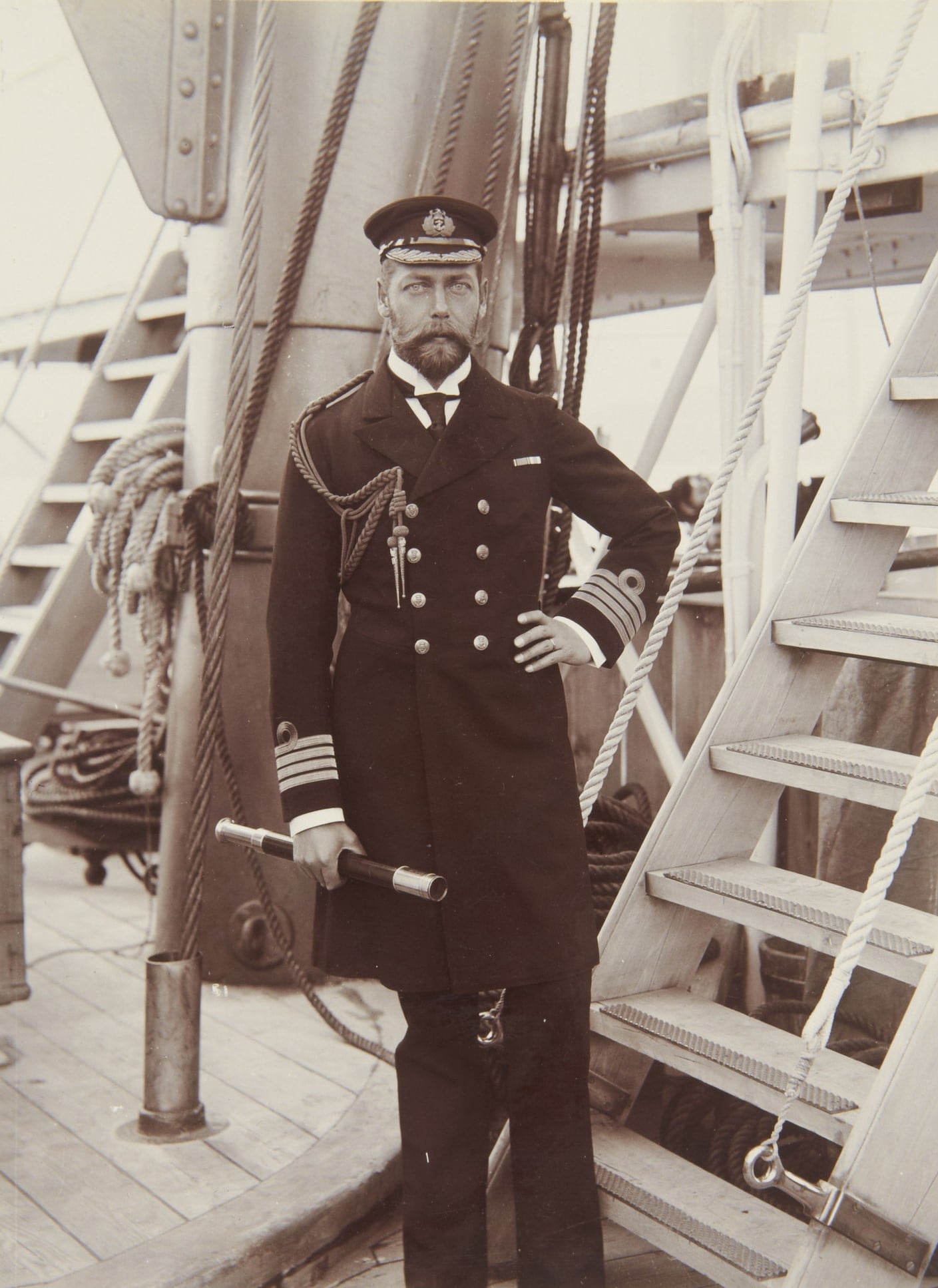 Chief Petty Officer Thomas M McGregor, George, Duke of York, later King George V (1865-1936), as Captain on HMS Crescent, Jun 1898 (RCIN 2581869) Photograph showing full length portrait of George, Duke of York, in uniform of Captain. He holds telescope in right hand; left hand on hip; taken on deck of HMS Crescent.