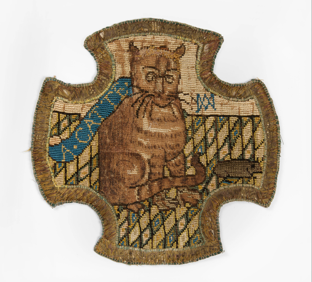An embroidered panel, of cruciform shape, depicting a ginger cat with a mouse on a chequered floor, bearing the cipher of Mary, Queen of Scots.