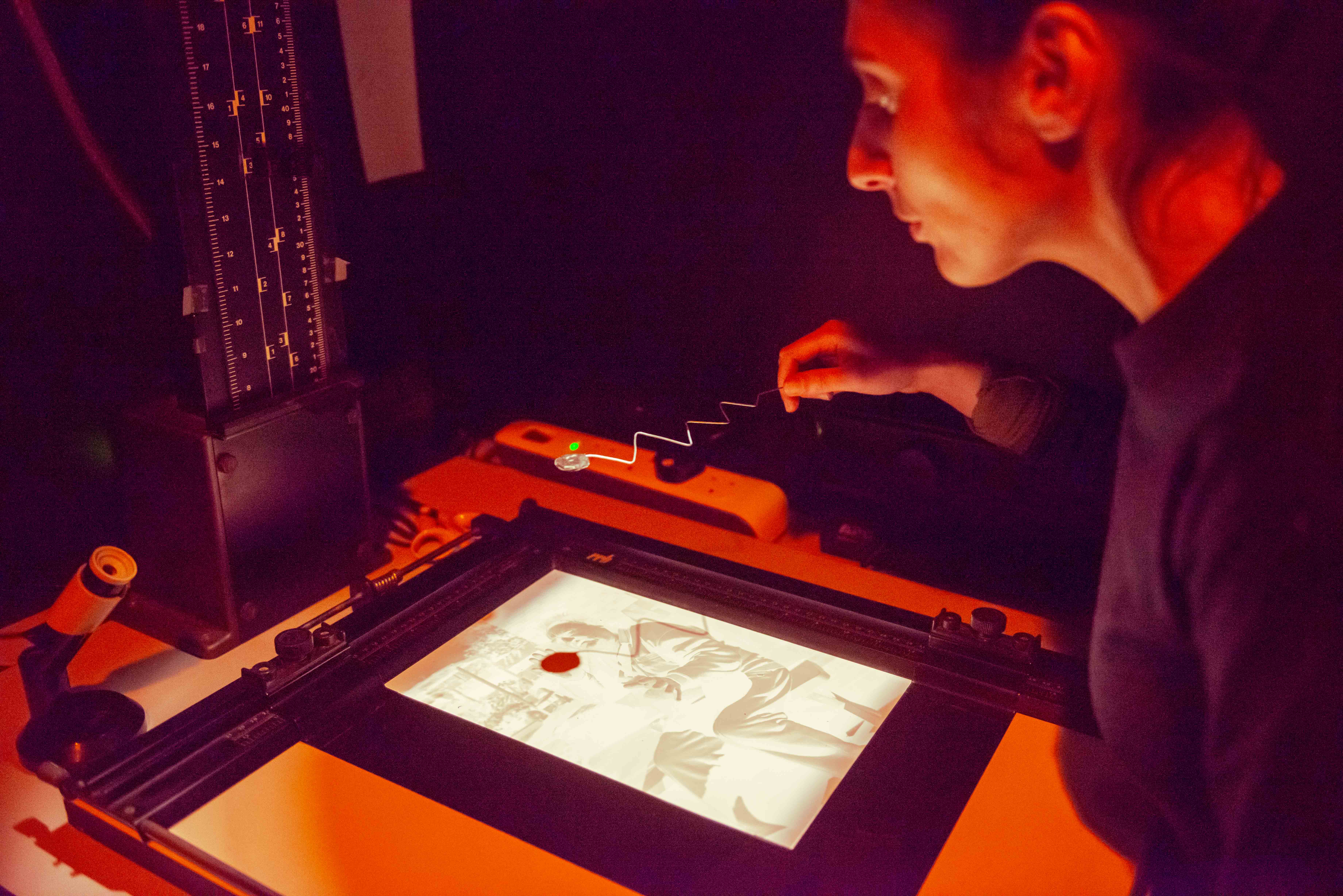 A contemporary photographer using a dodging tool during the printing process in the darkroom A contemporary photographer using a dodging tool during the printing process in the darkroom.