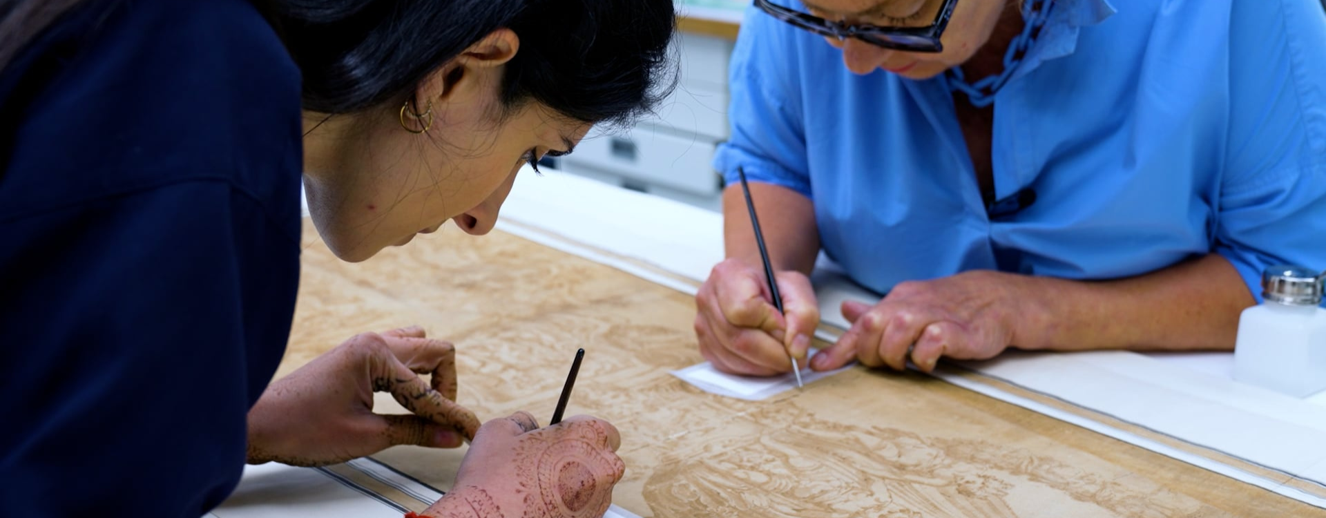 Paper conservators working on Marco Marchetti's drawing of a candelabrum.