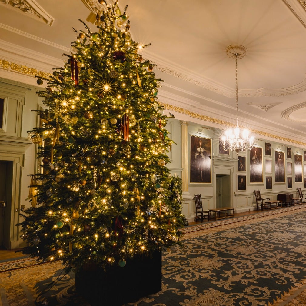 A large Christmas tree in a brightly lit historic interior