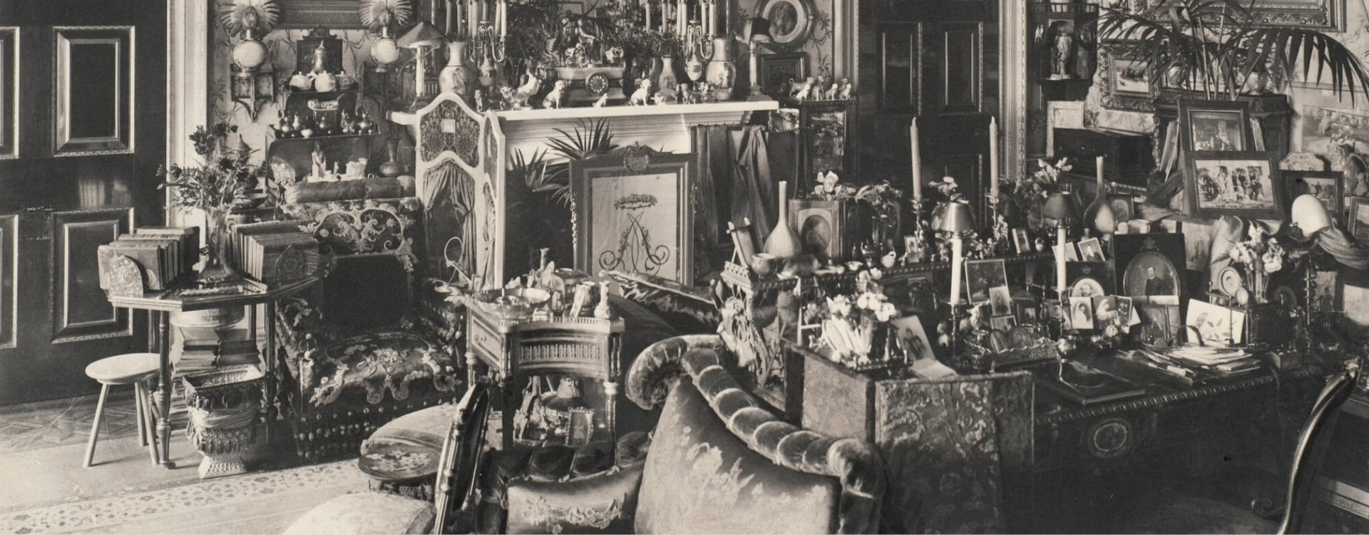 The Cluttered World of the Edwardians A black and white photograph of an Edwardian room filled with furniture, artwork and plants.