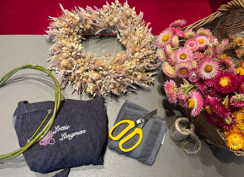 A dried floral wreath alongside tools needed to make it