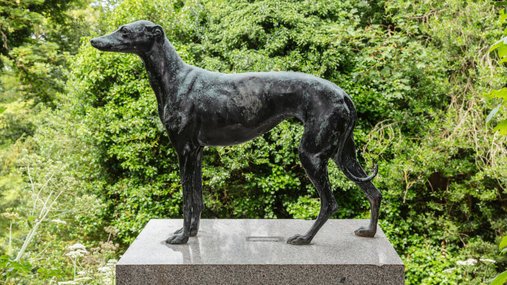 A bronze model of Prince Albert's greyhound Eos (1833-44) standing on a rectangular pink granite plinth on the terrace at Osborne House on the Isle of Wight.