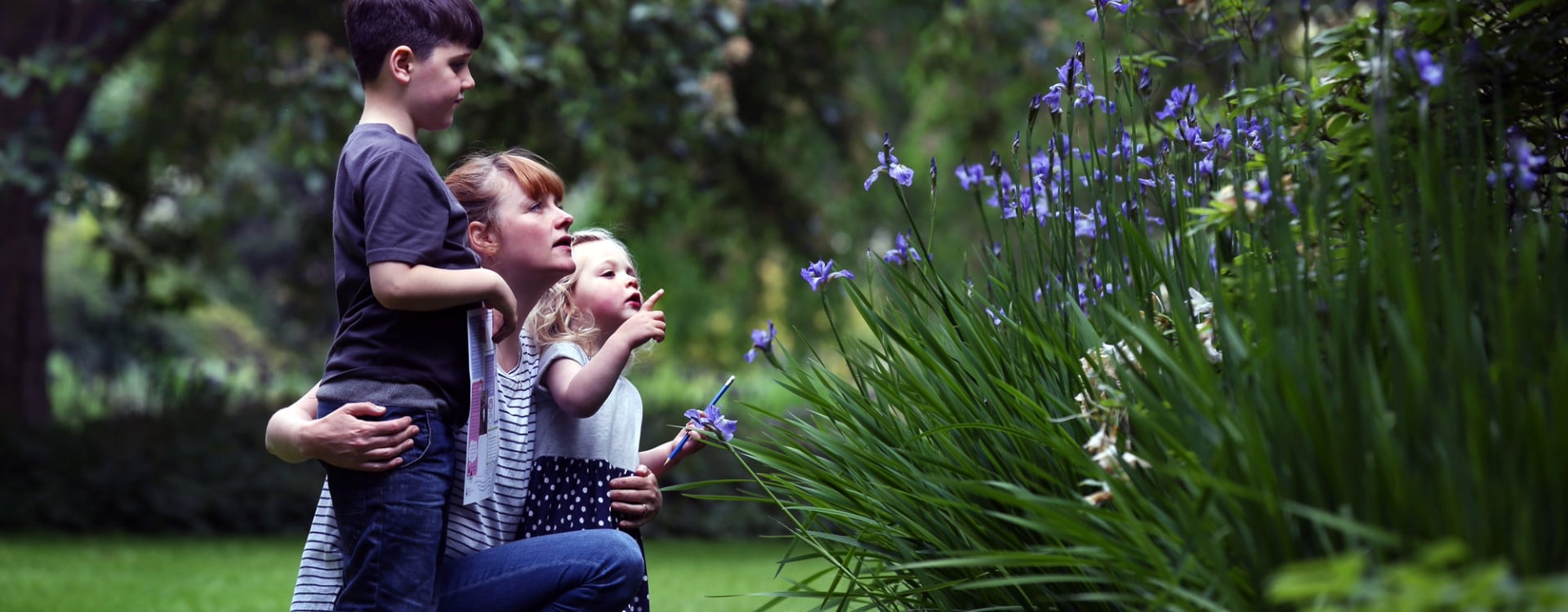 A woman and two children looking at plants